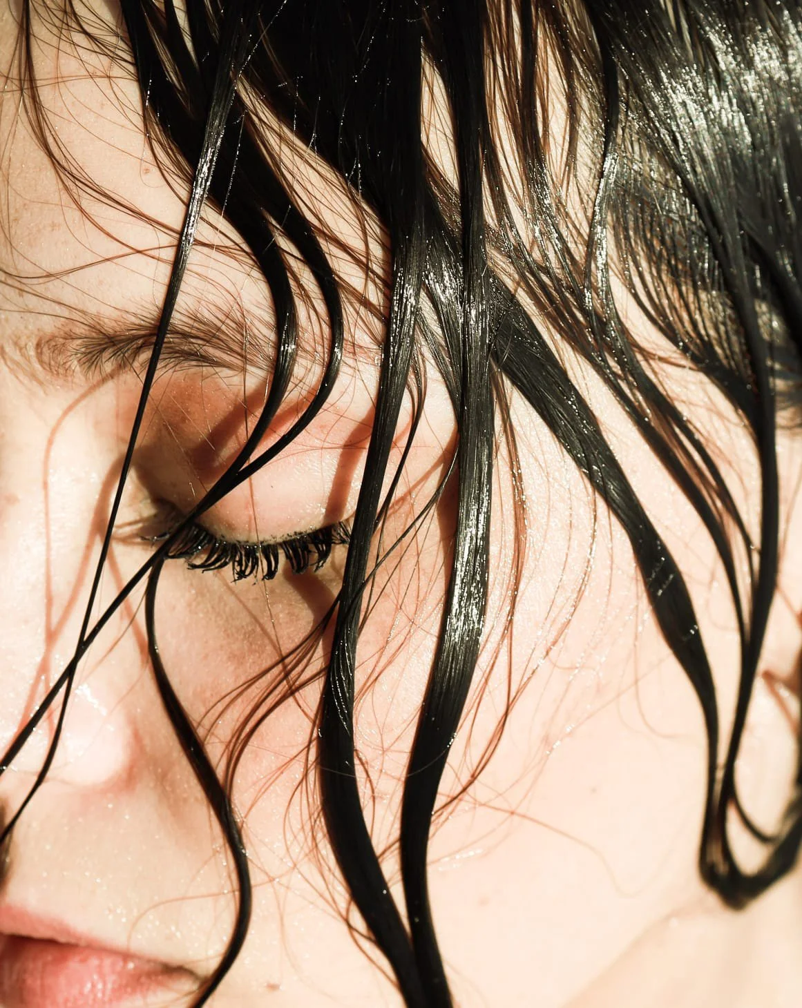 Donna con capelli bagnati che le coprono parte del viso.