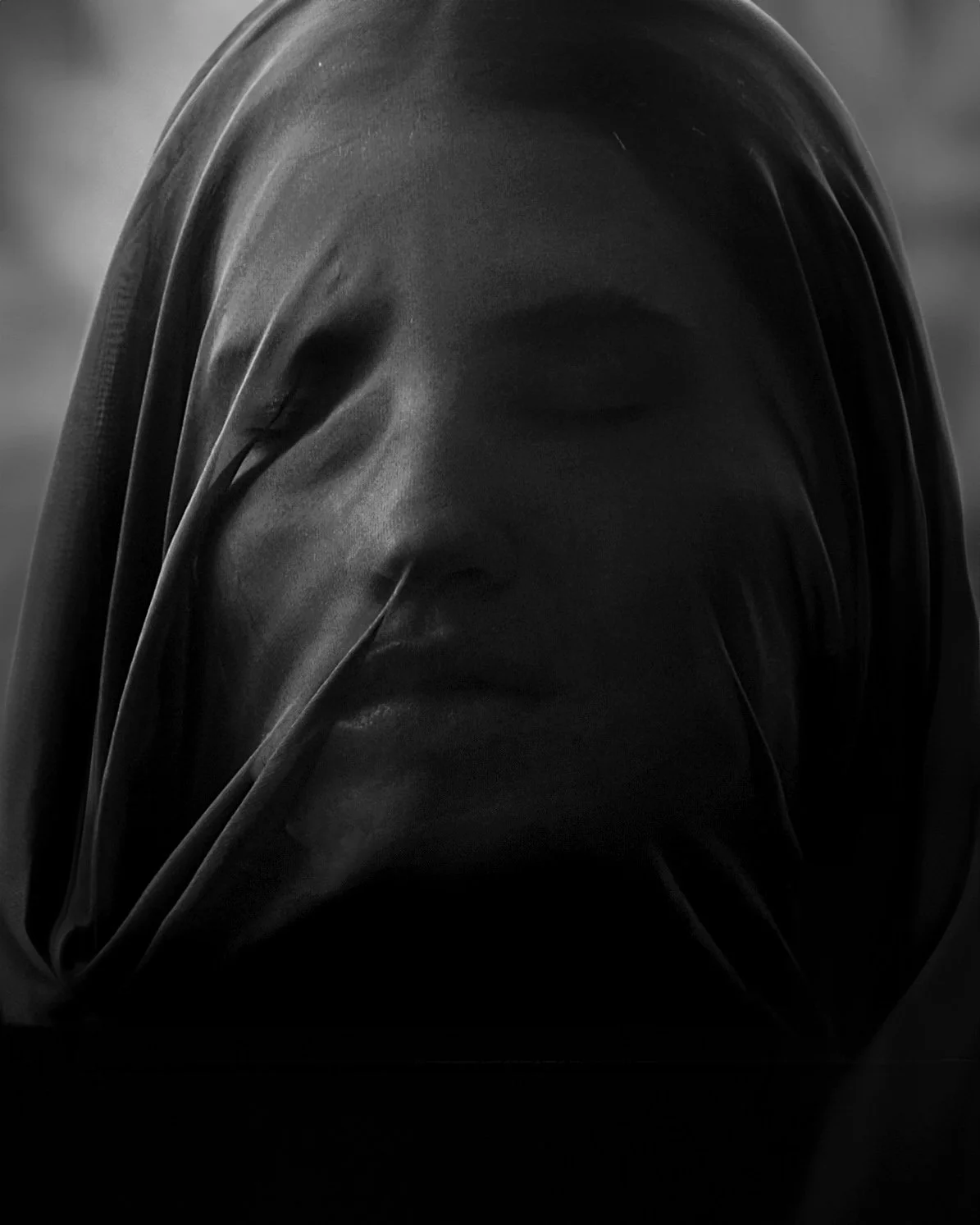 Volto avvolto in tessuto trasparente, espressione serena.