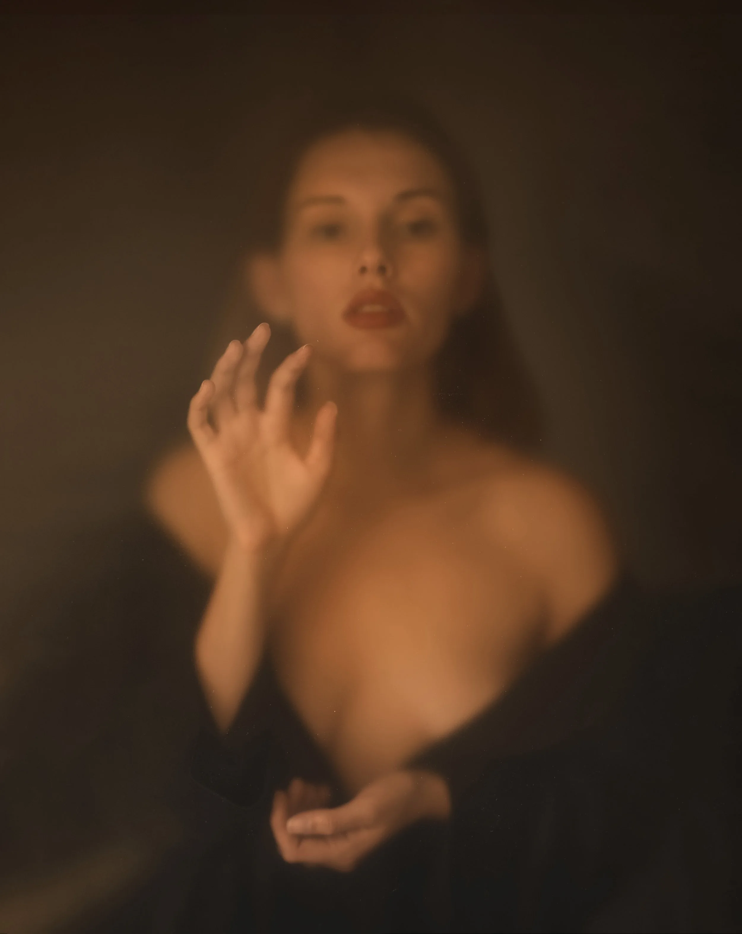 Donna sfocata dietro un vetro con mano sollevata e morbida luce marrone.