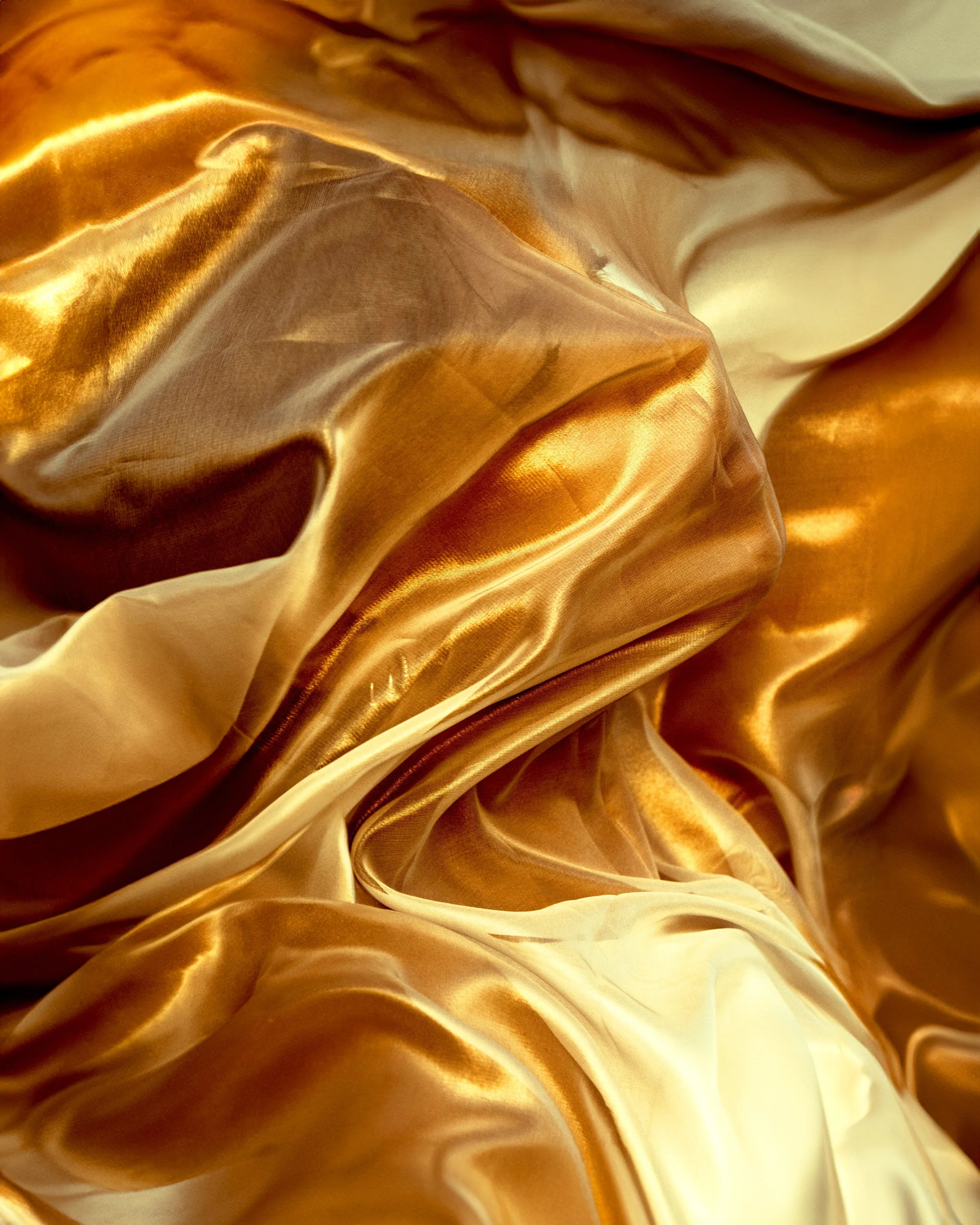 Tessuto in raso dorato con pieghe e riflessi di luce.