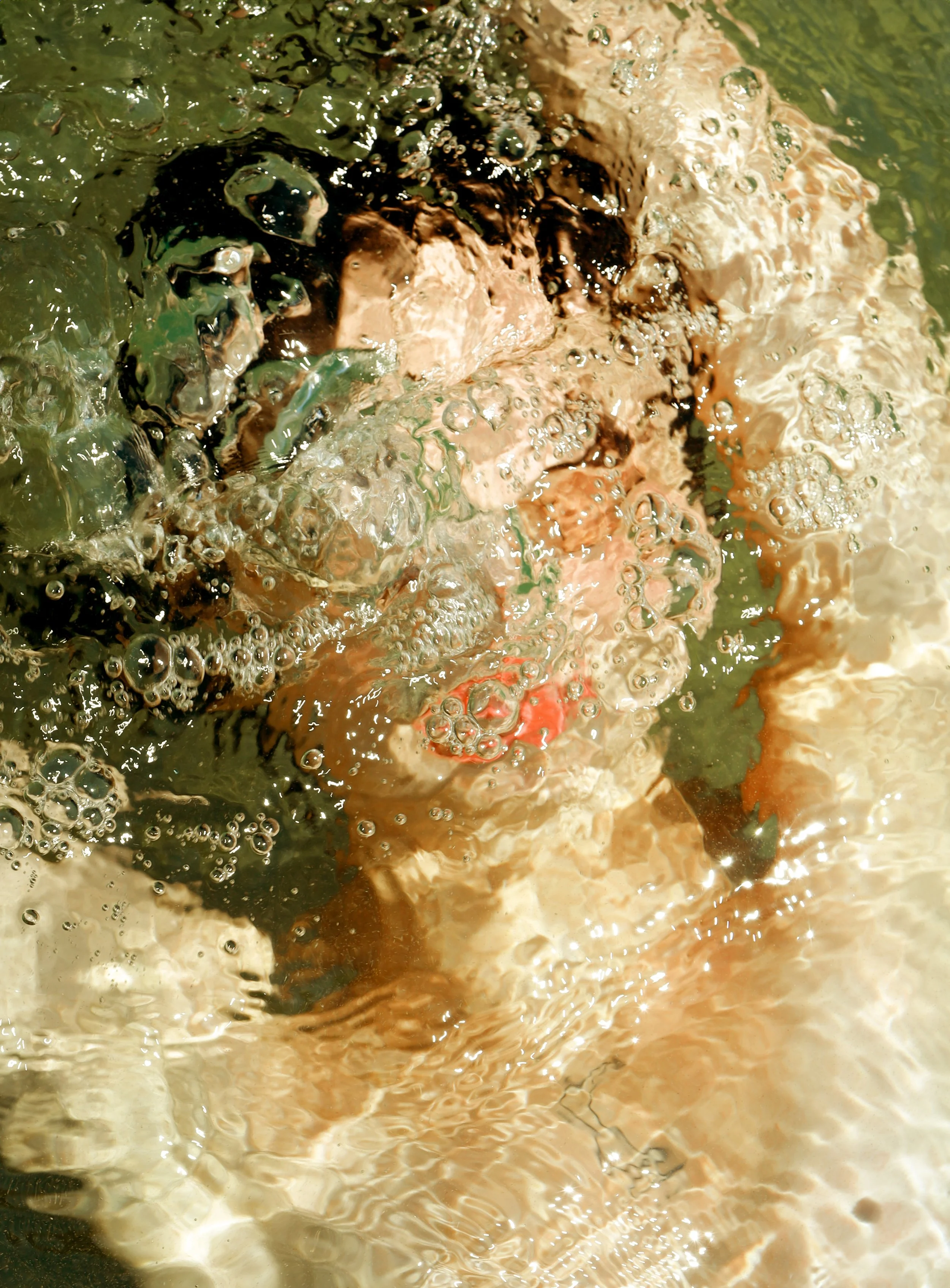 Persona sott'acqua con bolle d'aria visibili sulla superficie.