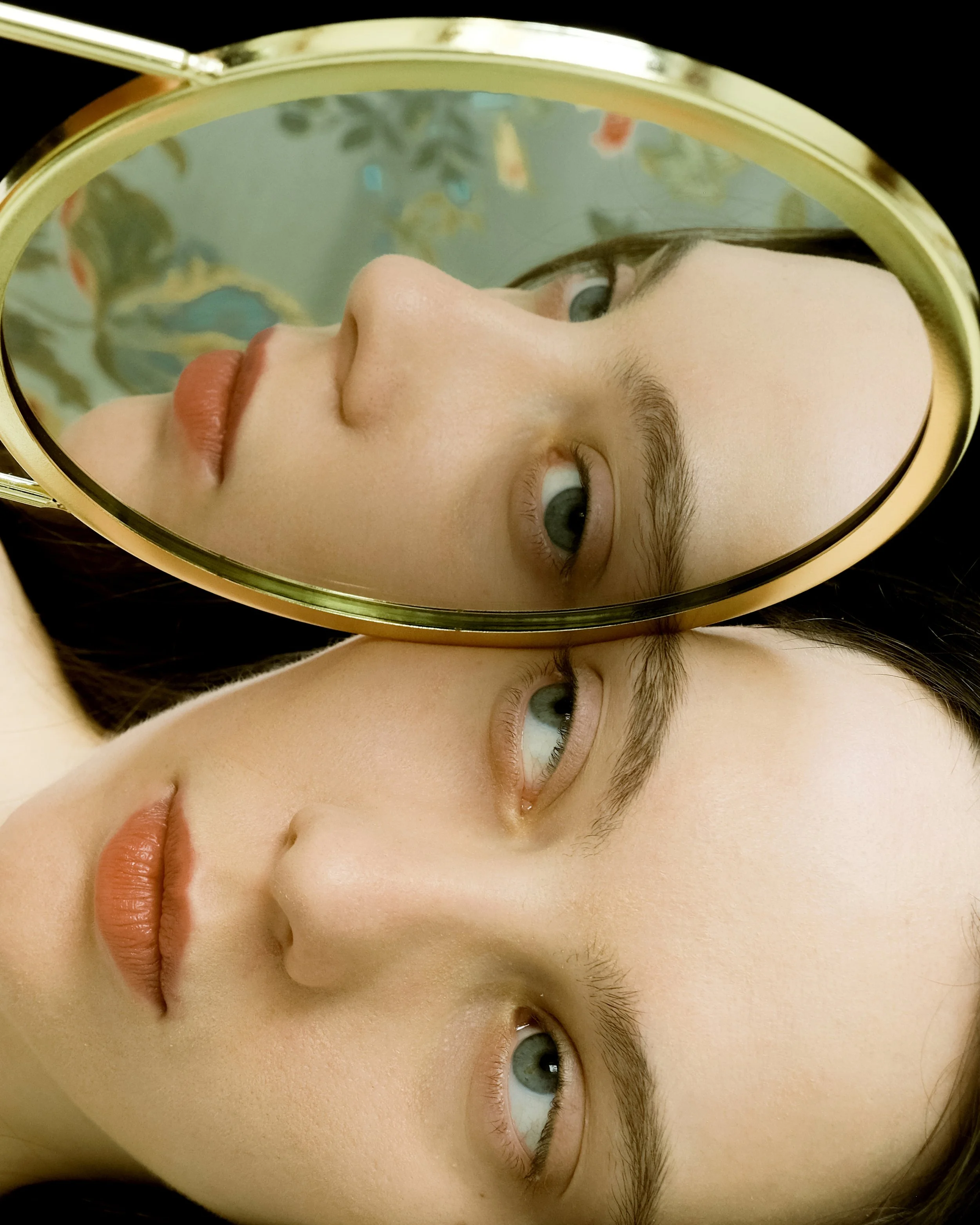 Riflesso del viso di una persona in uno specchio rotondo.