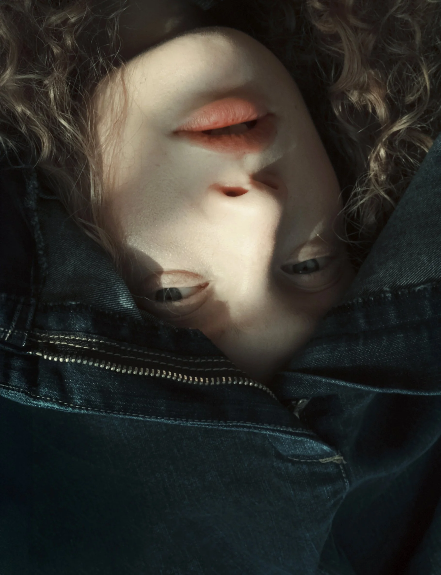 Primo piano di un volto parzialmente coperto da un tessuto di denim, orientato al contrario.