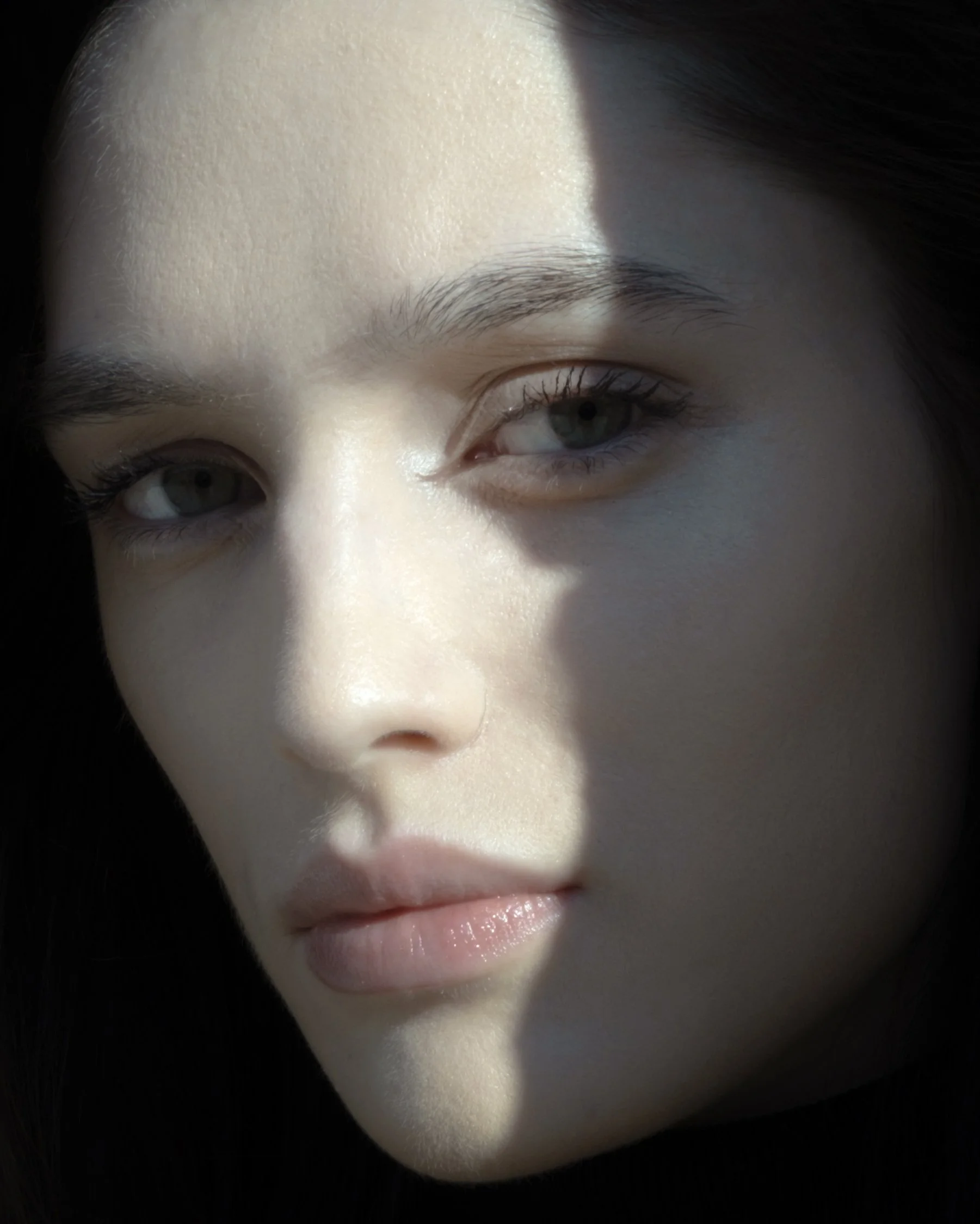 Primo piano di un volto femminile con parziale ombreggiatura.