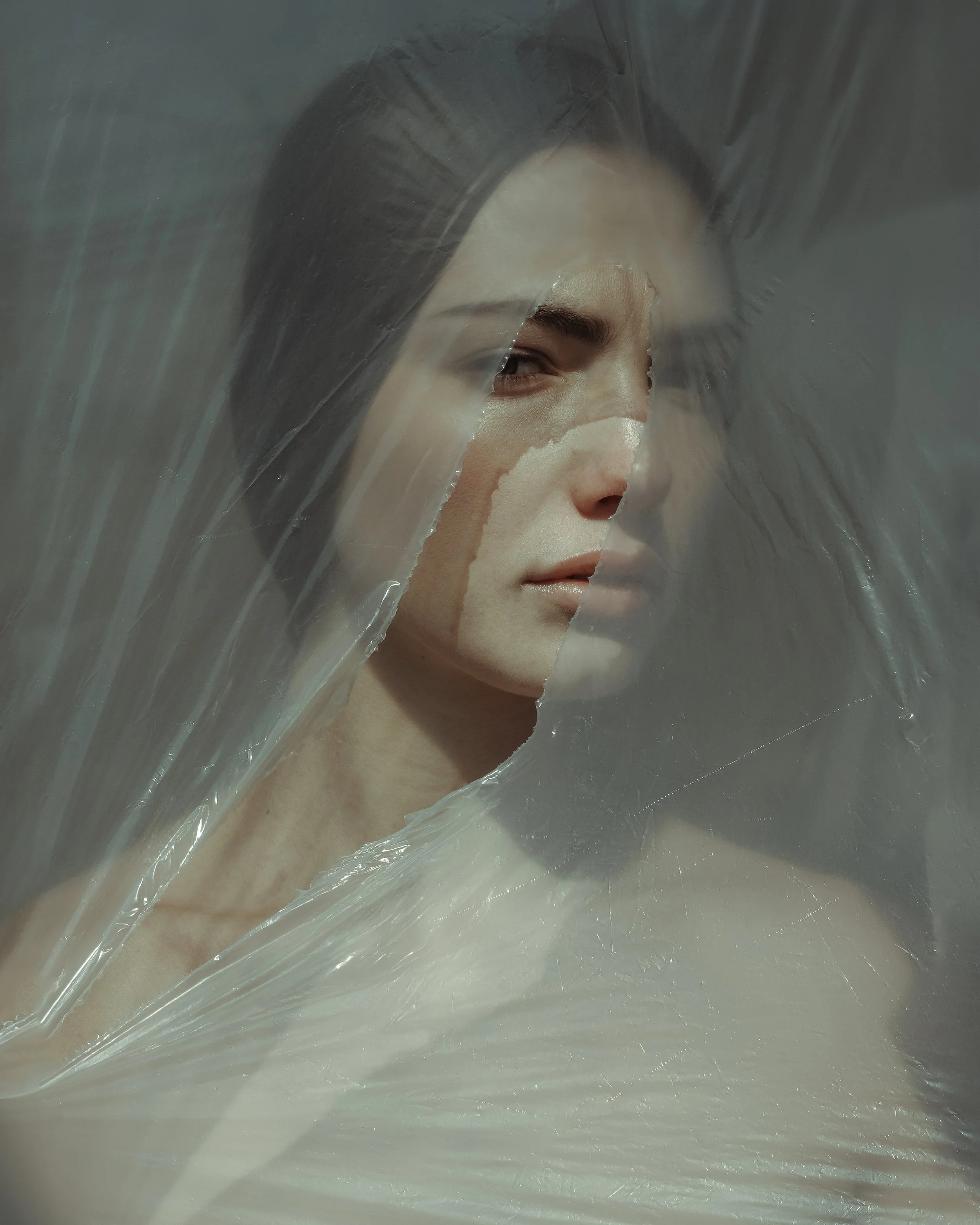 Ritratto artistico di una persona dietro un telo trasparente che copre il viso.