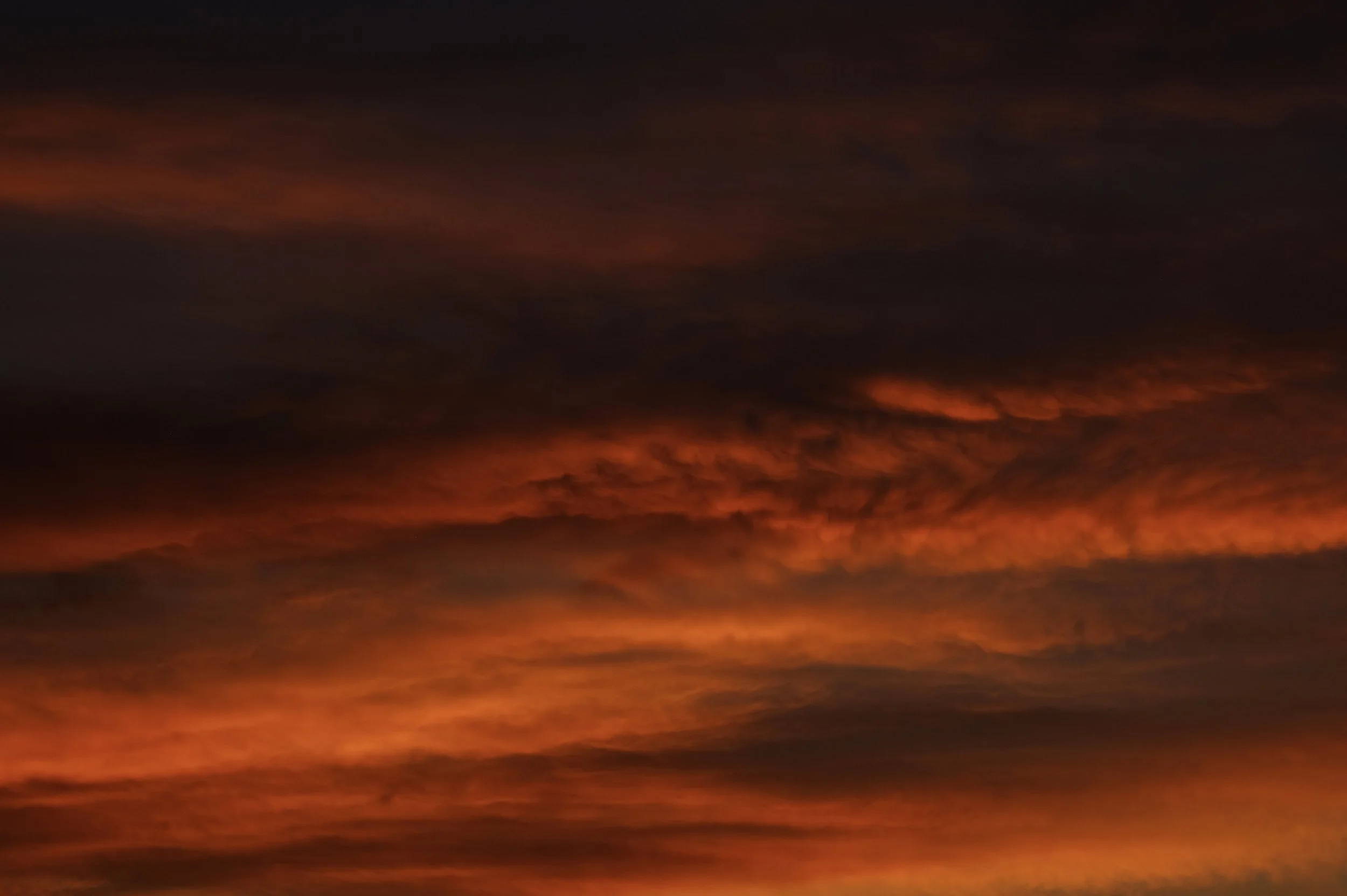 Cielo al tramonto con nuvole arancioni e sfumature rosse e viola.