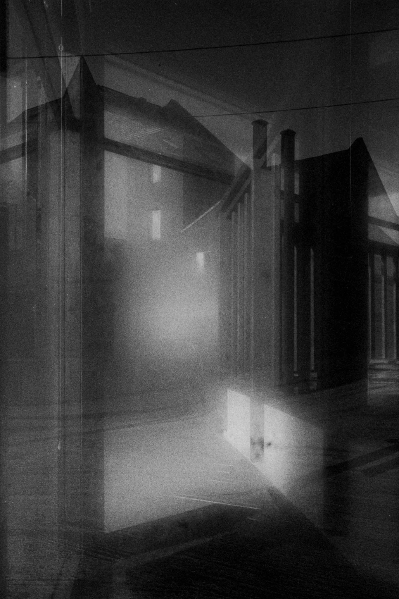 A black and white photo of an outdoor staircase and railing, with a misty or foggy atmosphere.