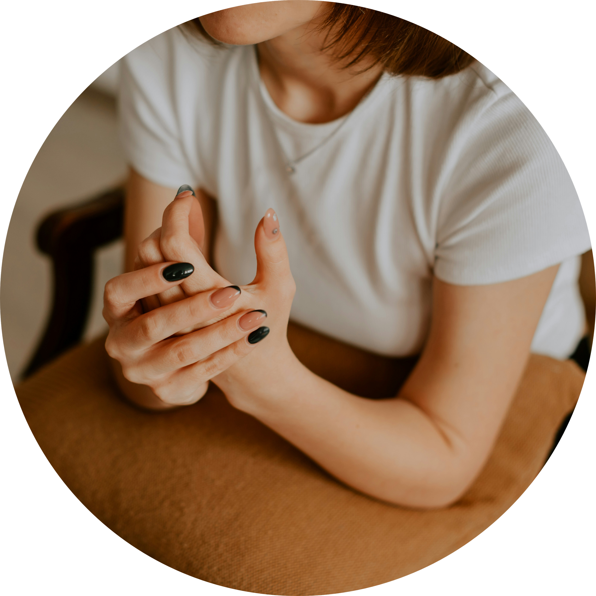 A woman seated quietly, hands gently clasped — a moment of reflection.
