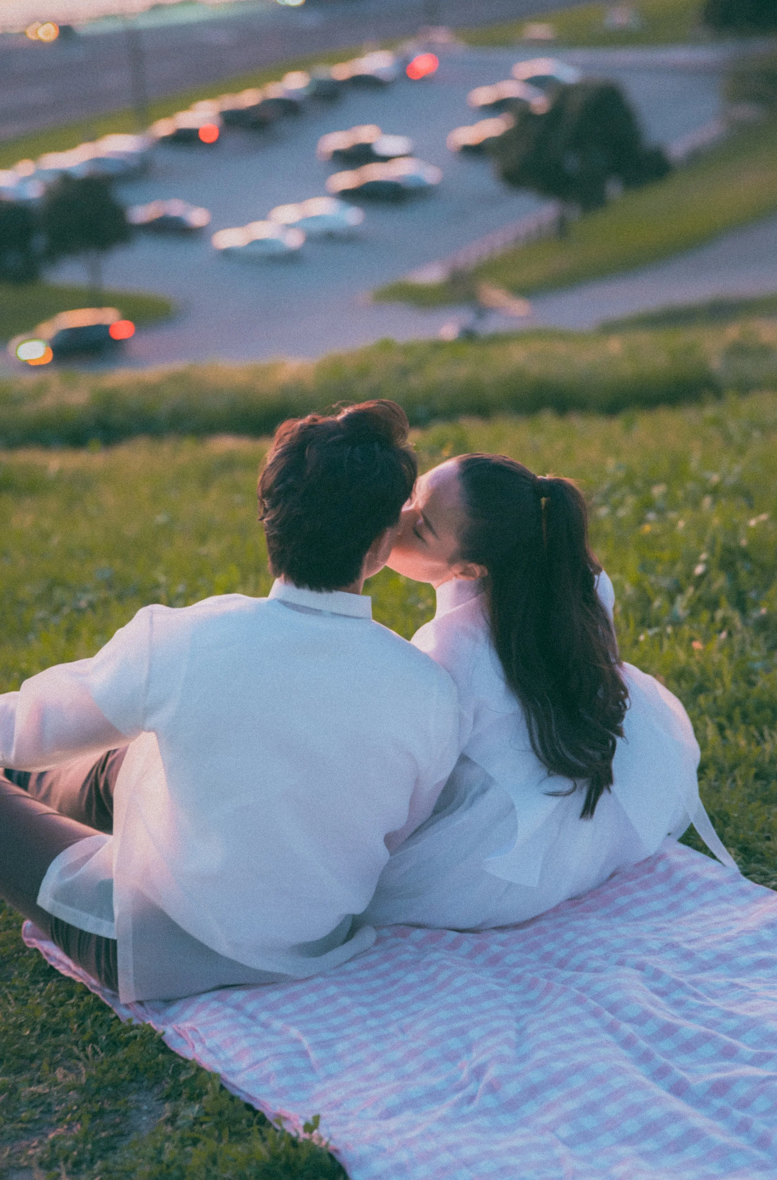 A newlywed couple sharing an intimate moment at a restaurant table with a large window and greenery in the background.