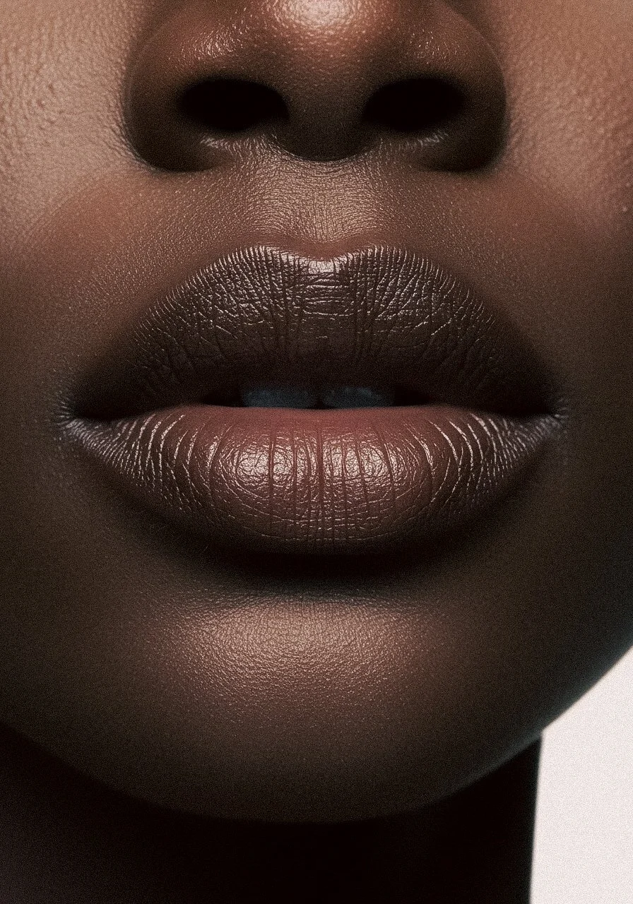 Close-up of a person's lips with metallic dark lipstick, focusing on the nose and lips, highlighting smooth skin and detailed texture.