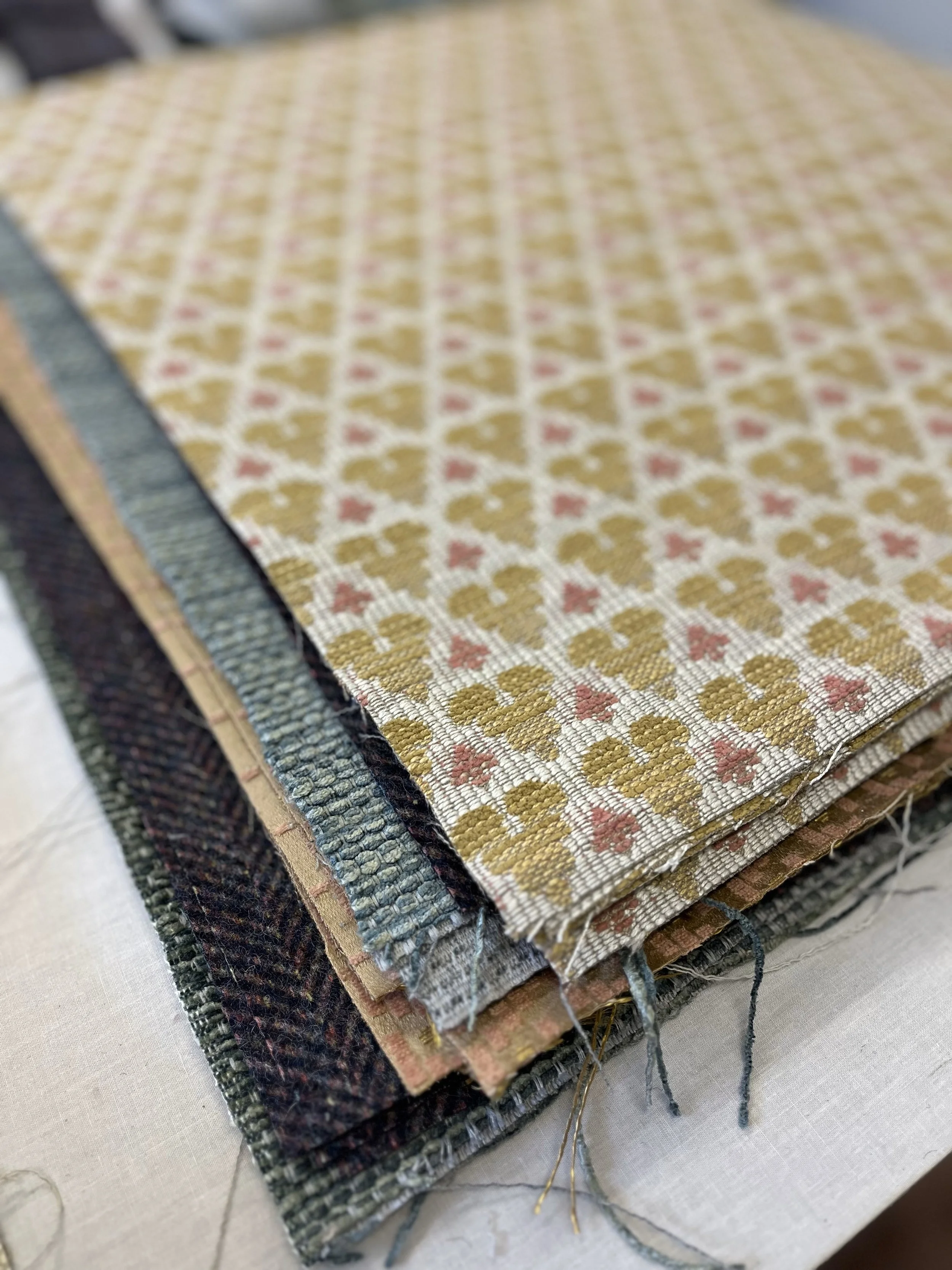 A stack of woven fabric swatches with various patterns and colors, featuring a geometric design on top.