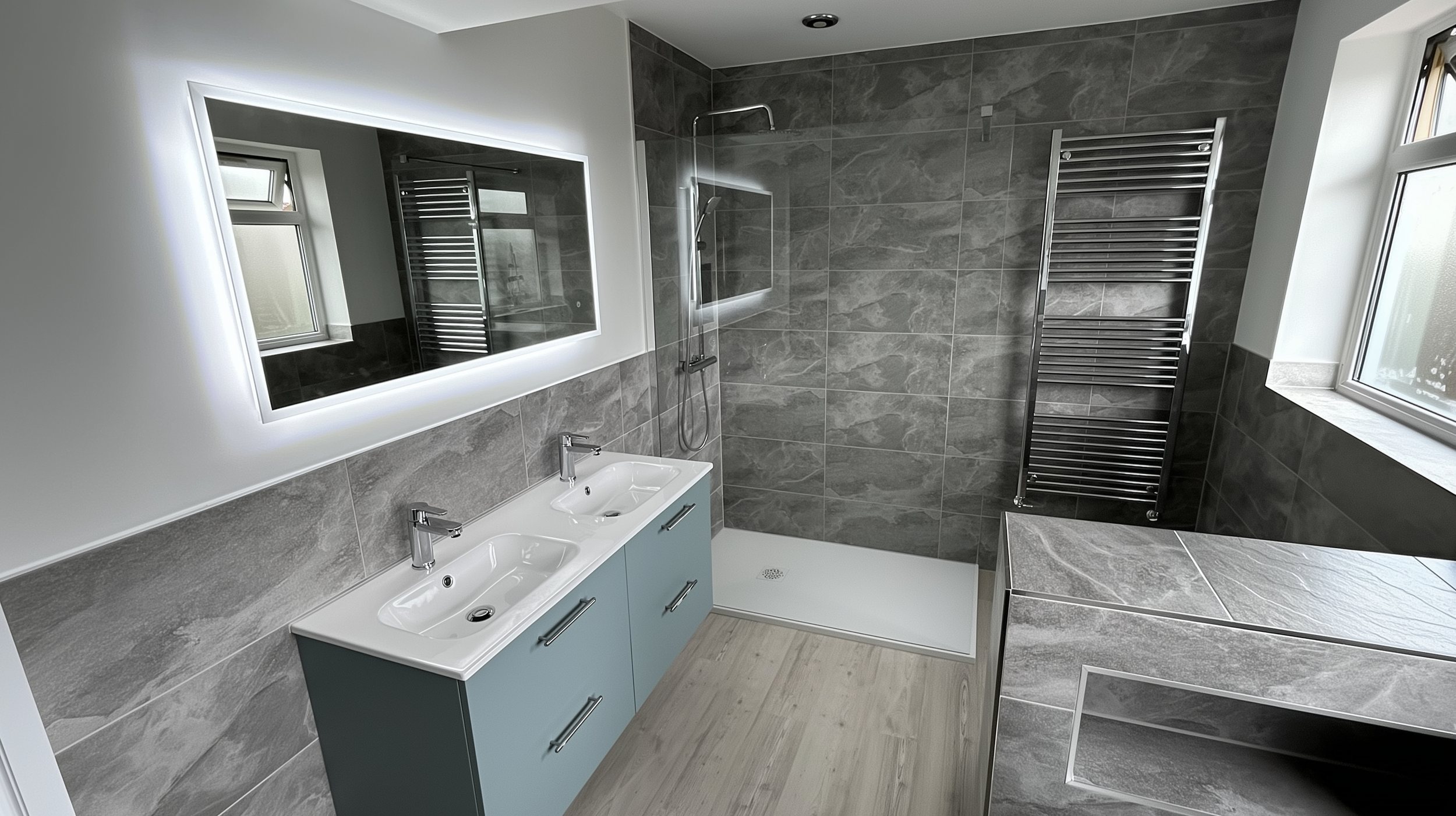 London bathroom installation featuring a glass walk-in shower, double-sink vanity, and grey wall tiles