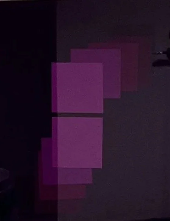 Multiple pieces of pink paper or cards arranged vertically against a dark background.