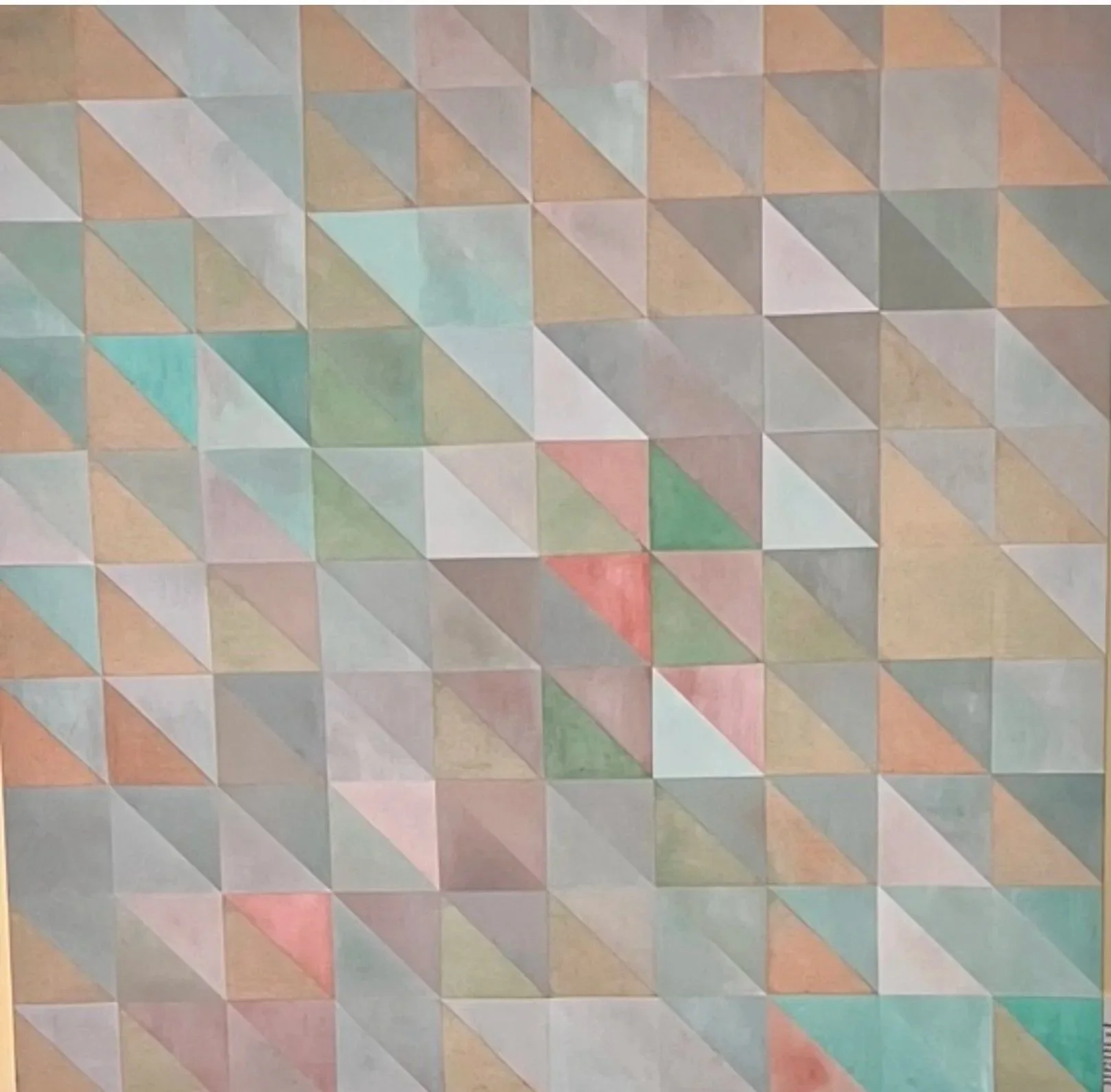 A wall with paint designed in geometric patterns consisting of various pastel colors in a triangular arrangement.