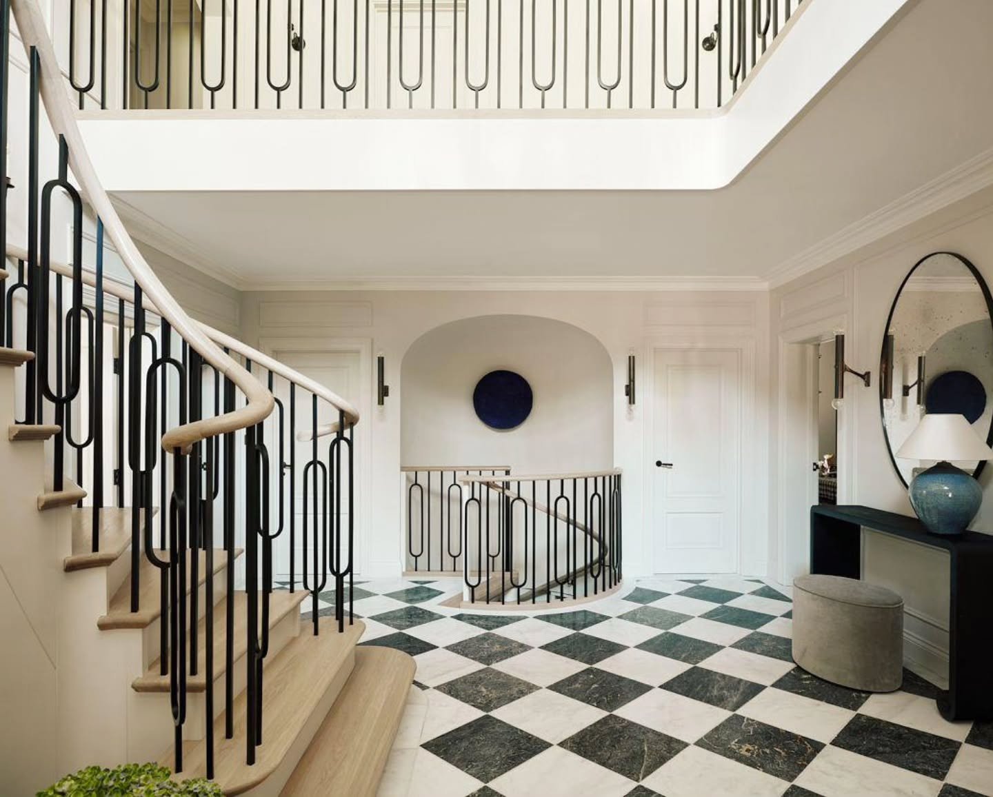 A completed project we're proud to share &mdash; this stunning entryway sets the tone for the rest of the home. From the custom wrought-iron railing with natural oak handrails to the dramatic black-and-white marble checkerboard floor, every detail wa