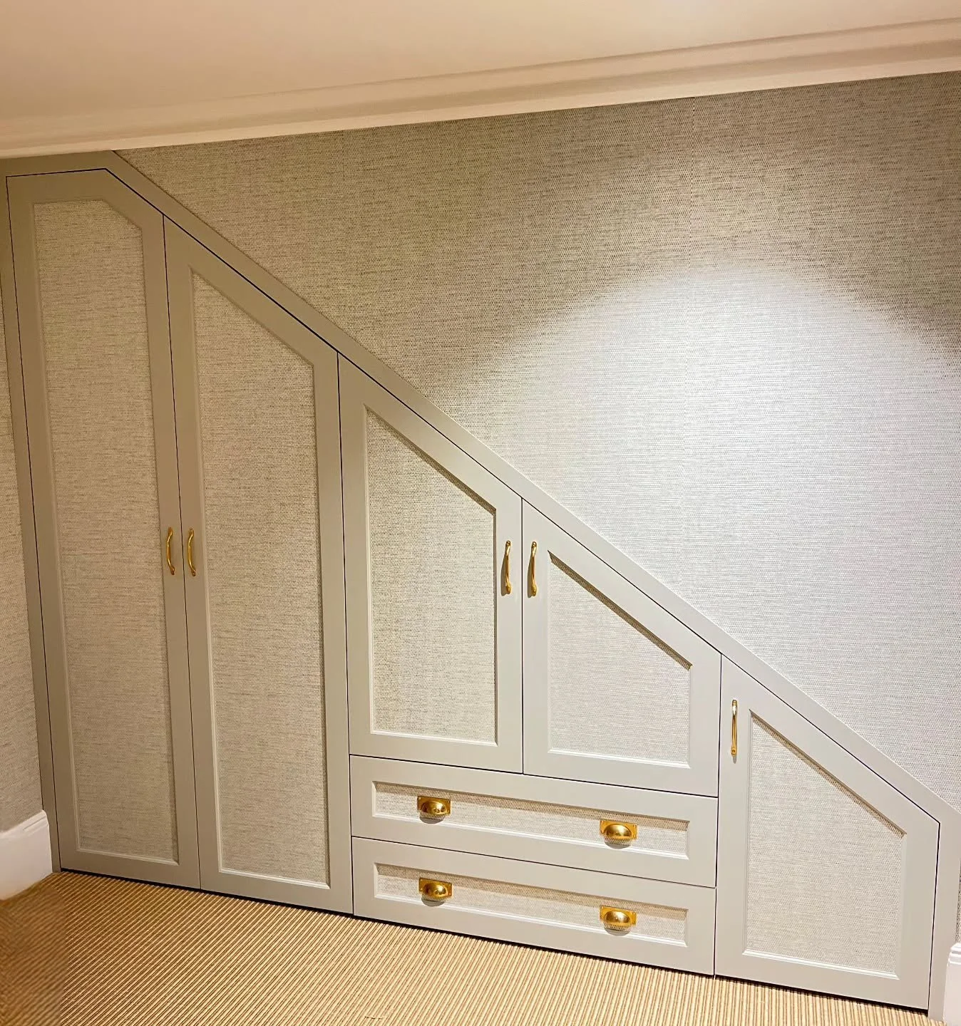 Bespoke MDF shaker understairs unit, hand-painted in Fenwick &amp; Tilbrook &ndash; Blakeney Point and finished with matching wall-covering for a seamless look. Angled wardrobes are all about precision &mdash; getting the dimensions right and maximis