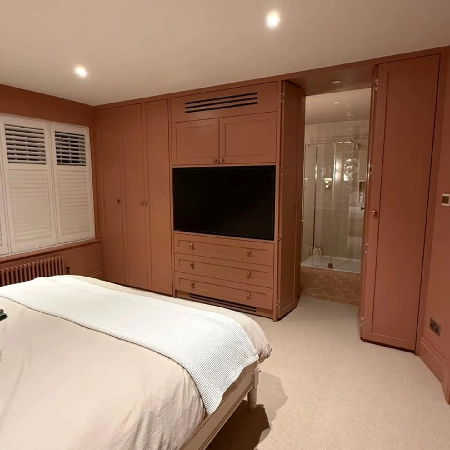 Our Chiswick project, bespoke shaker wardrobes painted in Farrow &amp; Ball, complete with a hidden door using invisible Soss hinges for a seamless look. The TV sits on an electric bracket, revealing the AV equipment tucked neatly behind. Smart desig