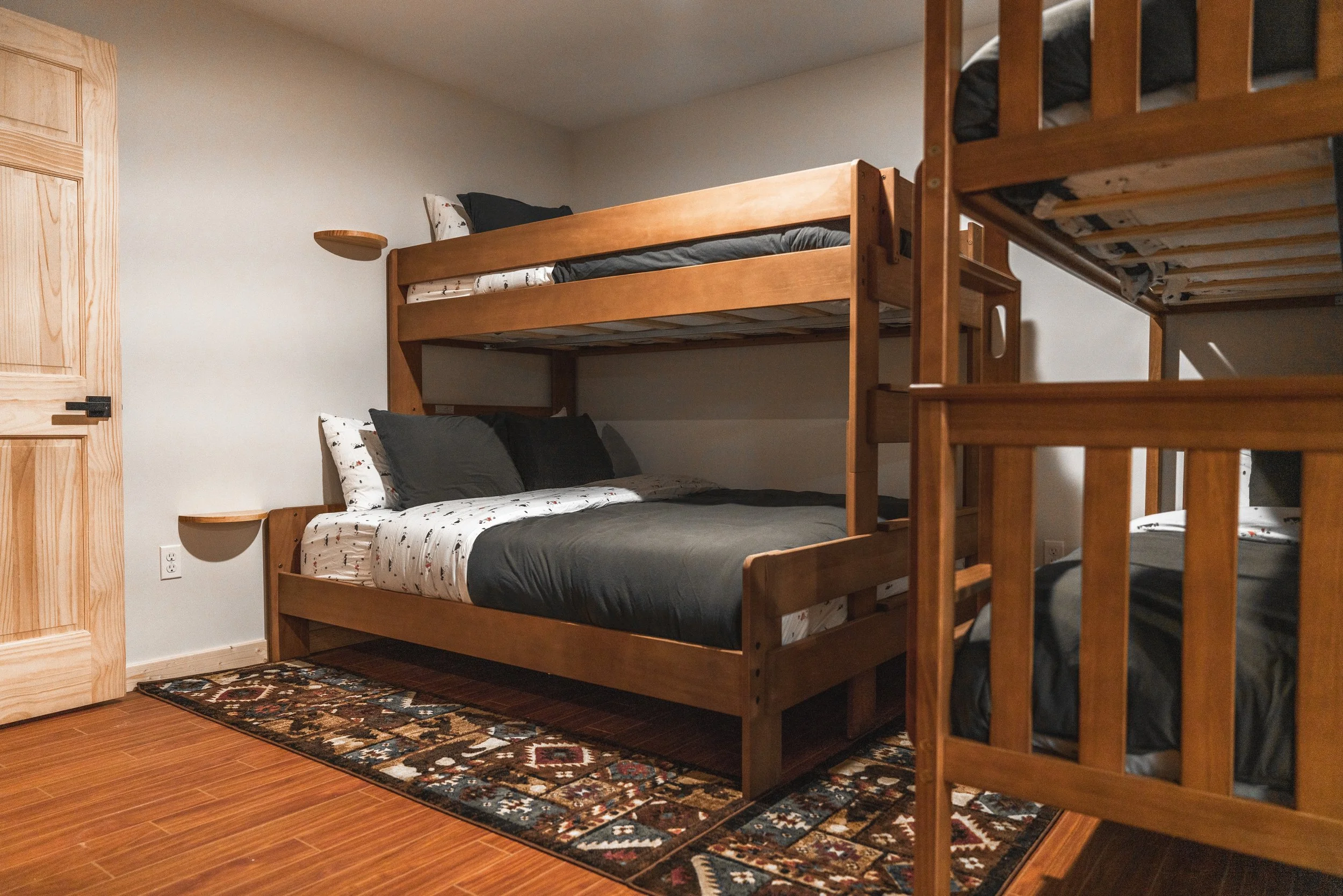 A room with wooden bunk beds and a patterned rug on the floor.
