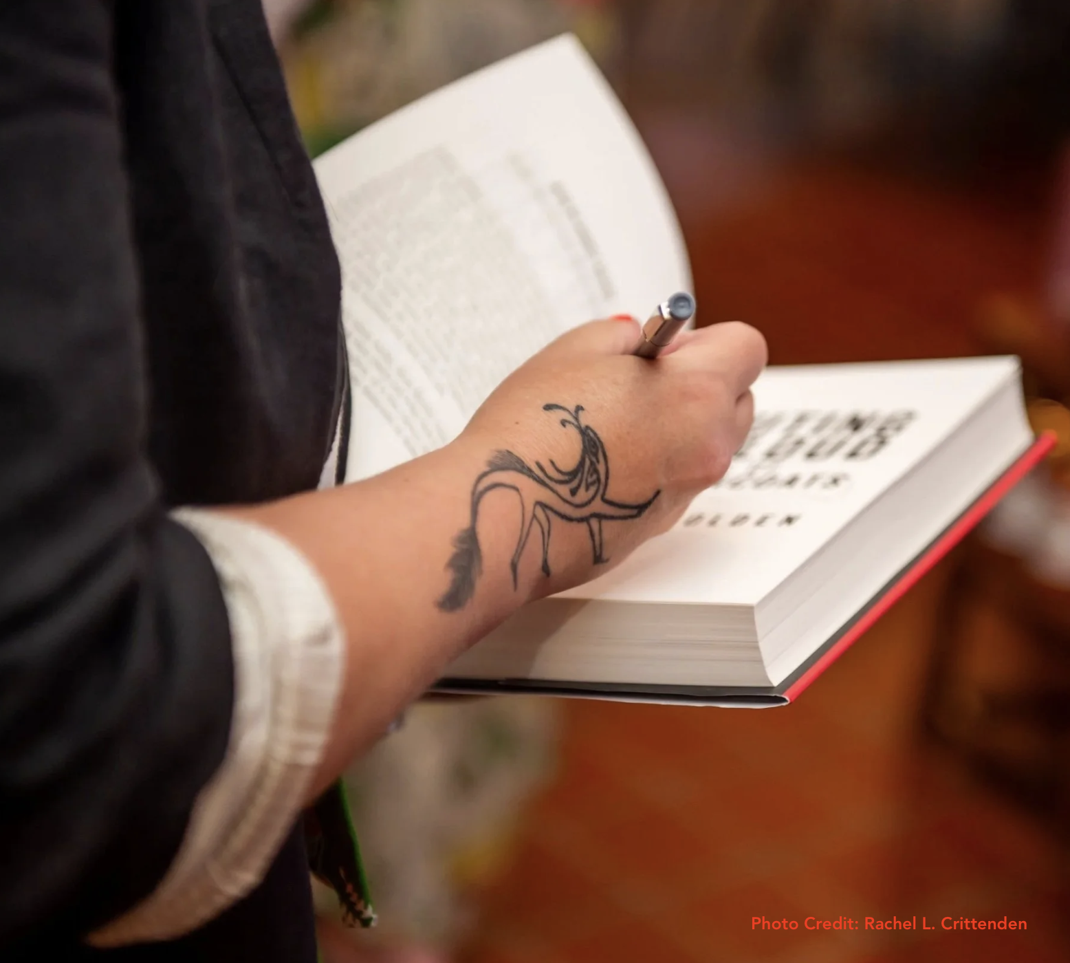author's hand signing a physical copy of one of her books