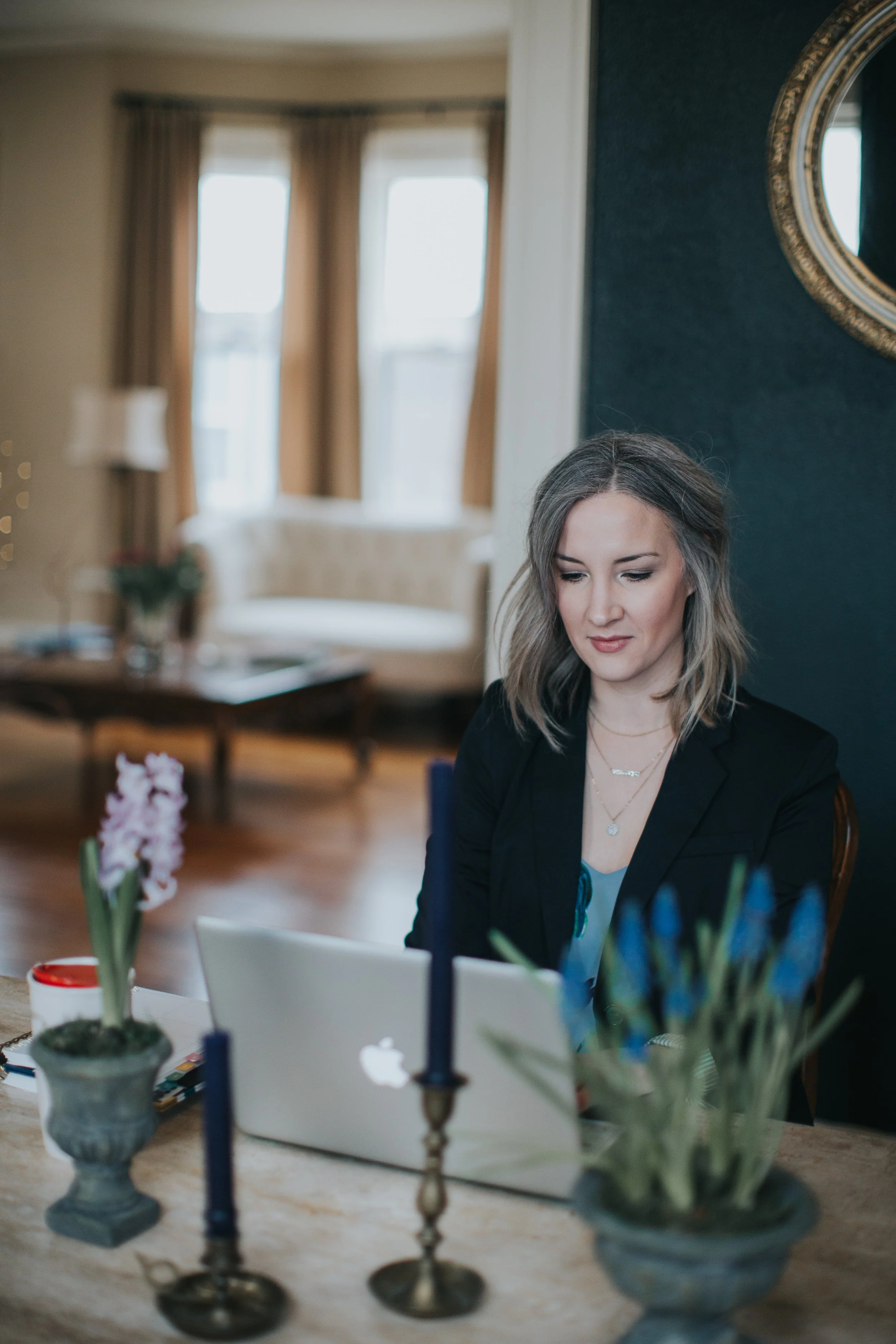 Interior designer seated at a dining table styled with potted spring bulbs and antique candlesticks.
