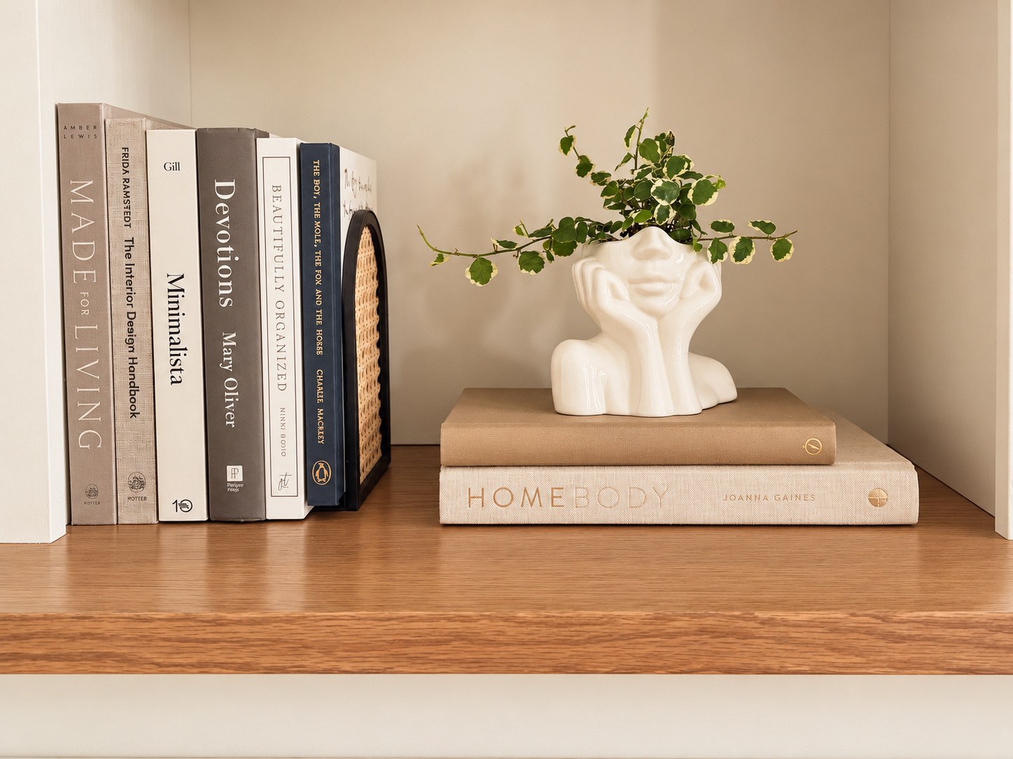 Styled wooden bookshelf featuring neutral design books, a sculptural white ceramic planter, and greenery, showcasing thoughtful interior styling by Summer Glen Design in Sioux City, Iowa.