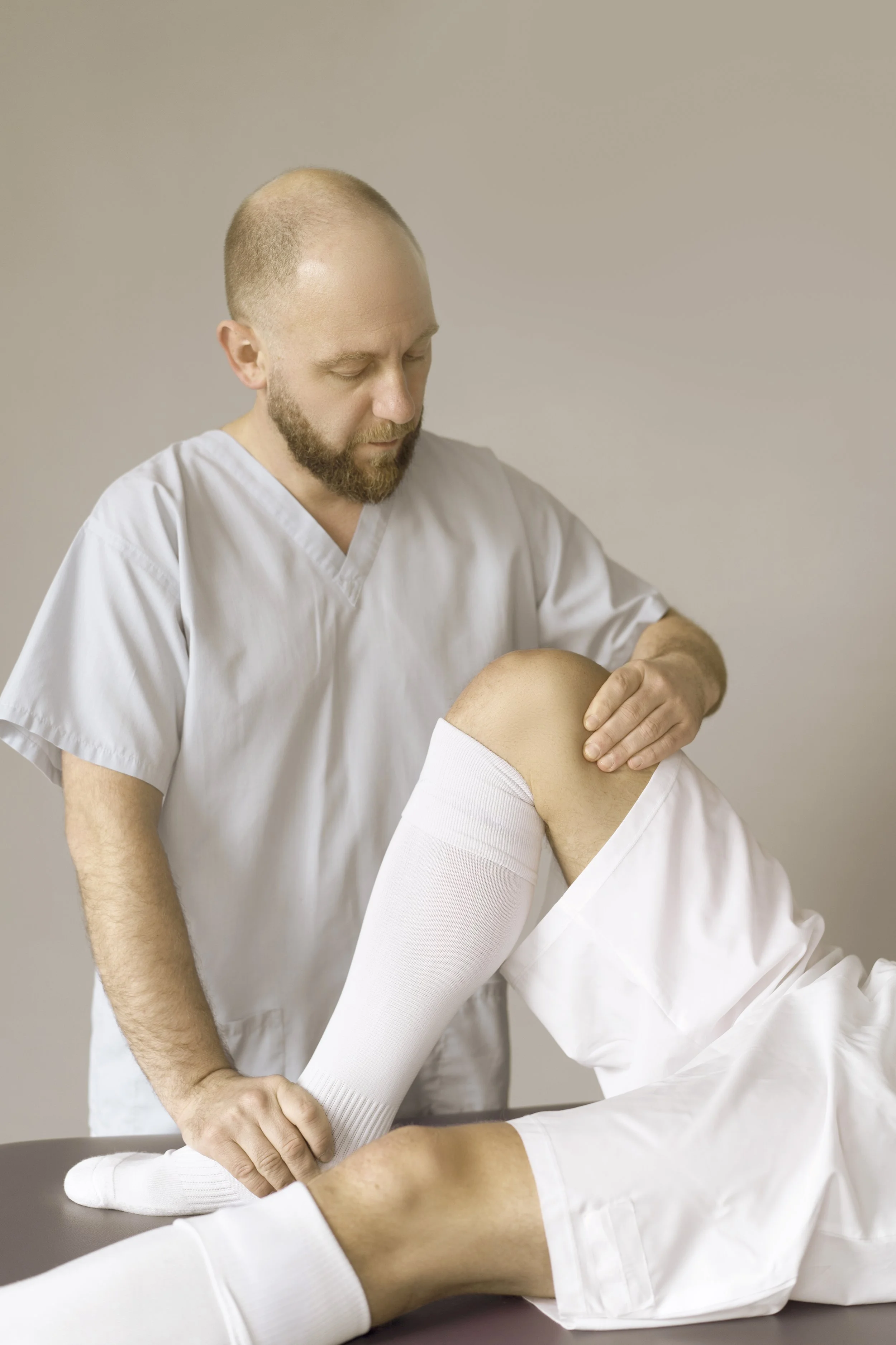 Medical professional examining a patient's knee.