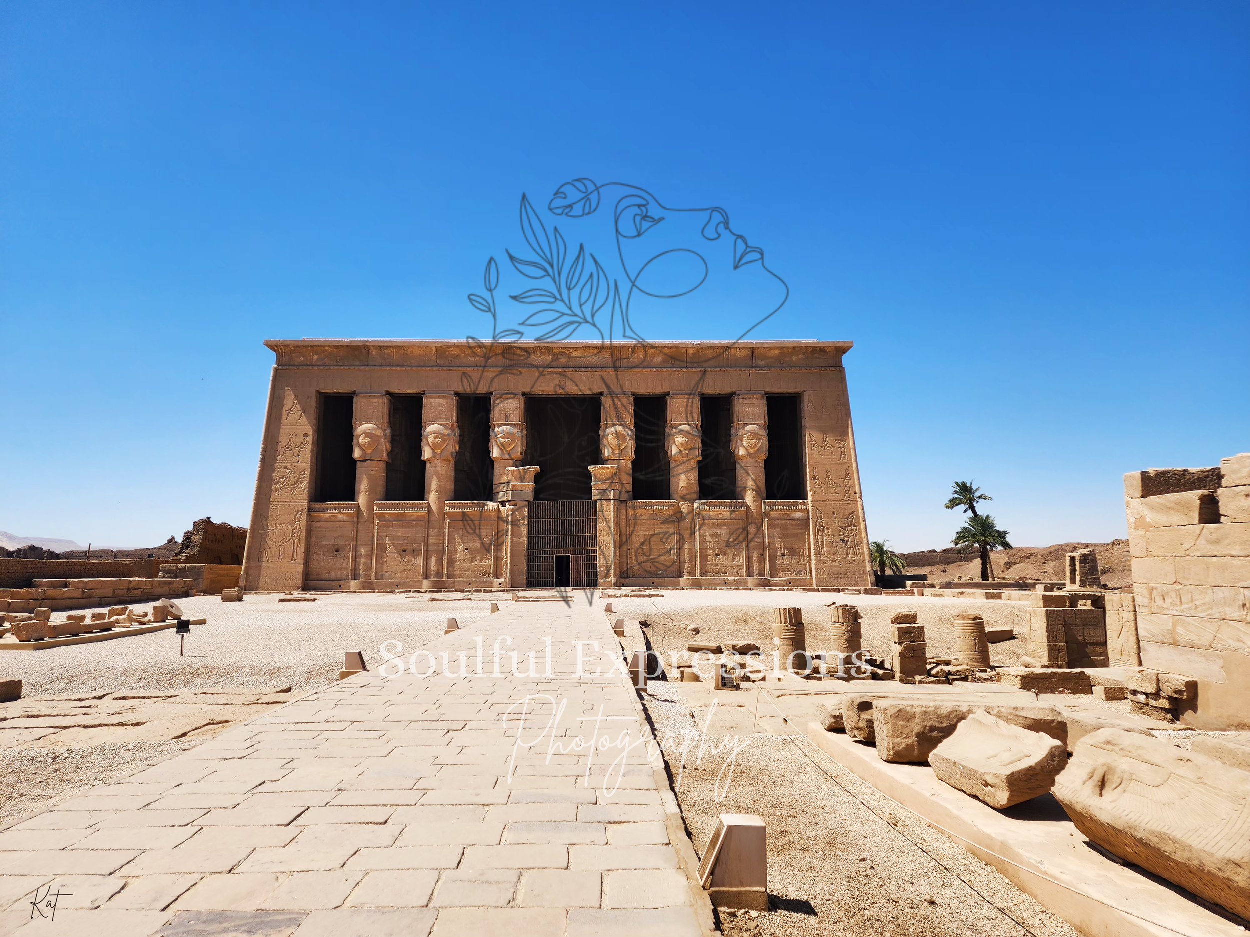 The Dendera Temple in Egypt with large stone pillars, hieroglyphic carvings, a paved pathway leading towards it.