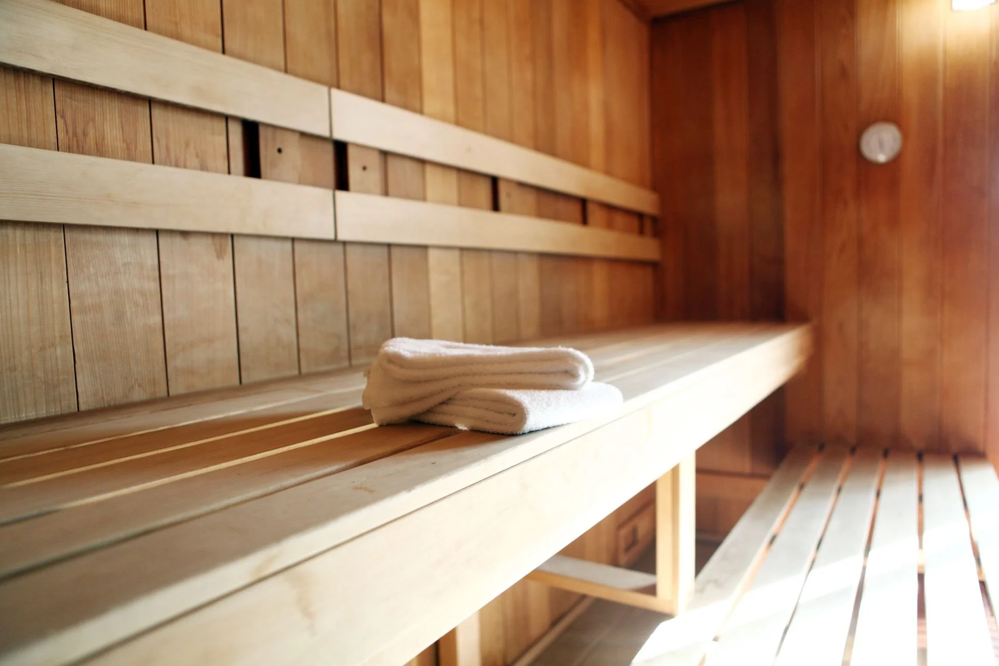 Empty wooden sauna with folded towels on a bench.