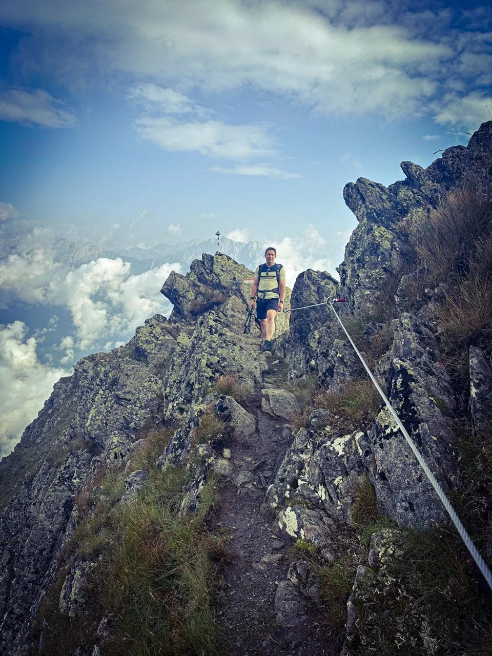 Hiker on a rocky mountain ridge with clouds in the background