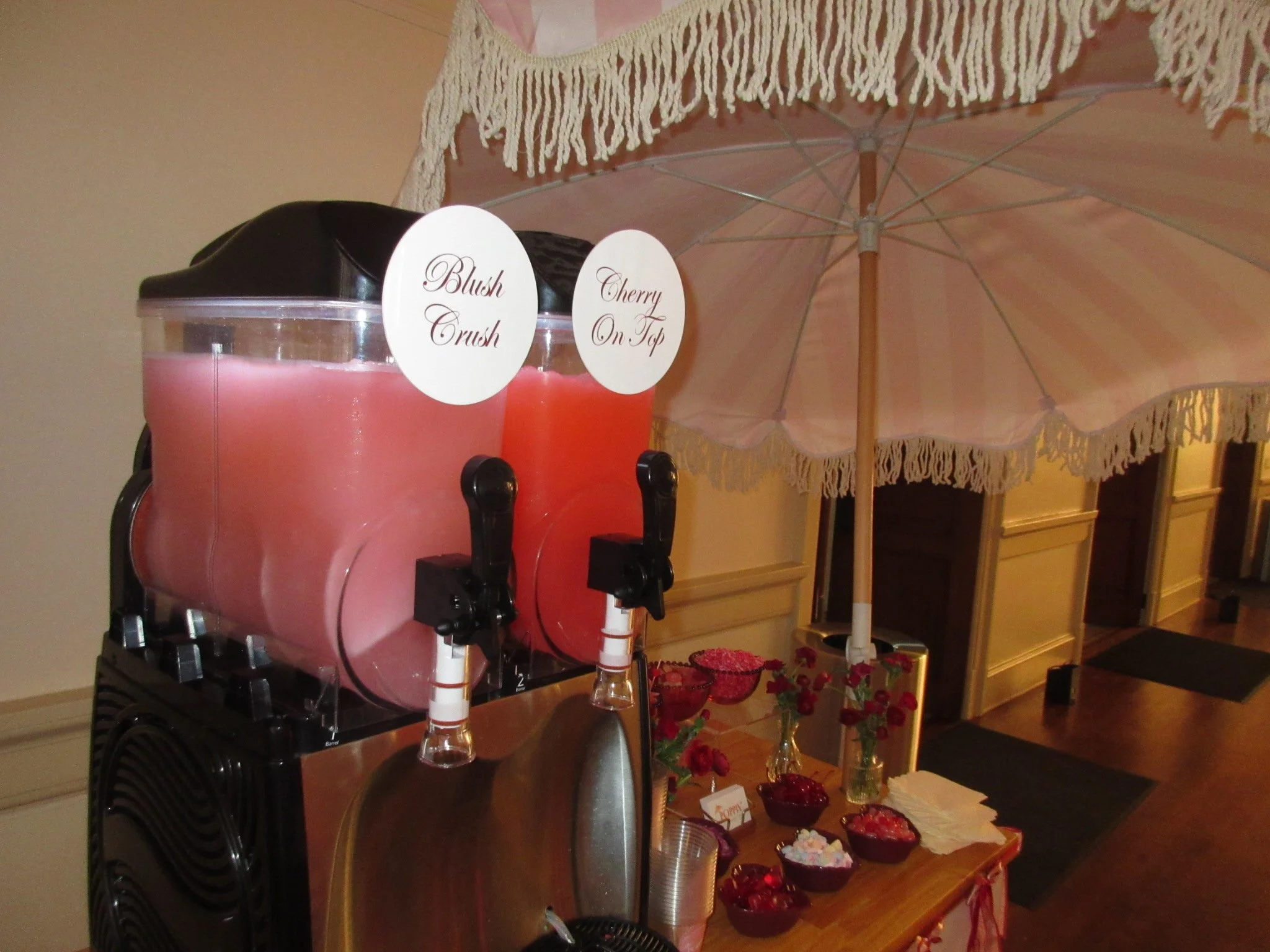 Four colorful cocktails on a ledge with flowers, in an outdoor setting, featuring a variety of garnishes.
