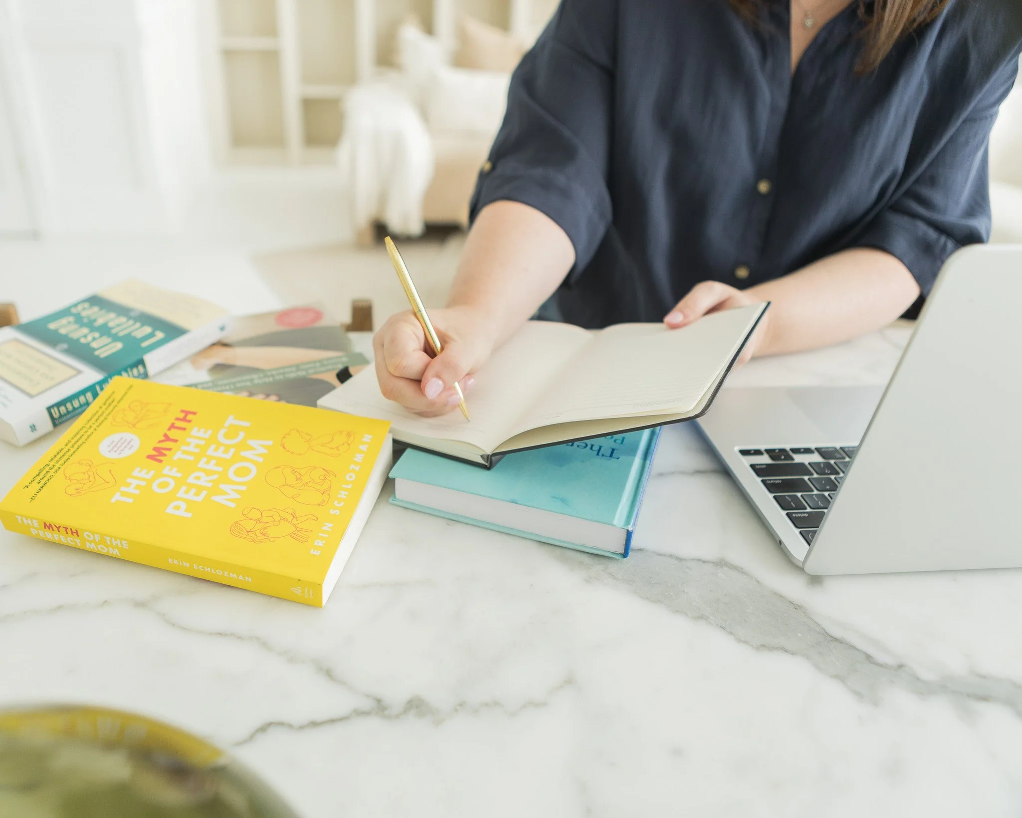 
hands writing in a journal beside pregnancy book
