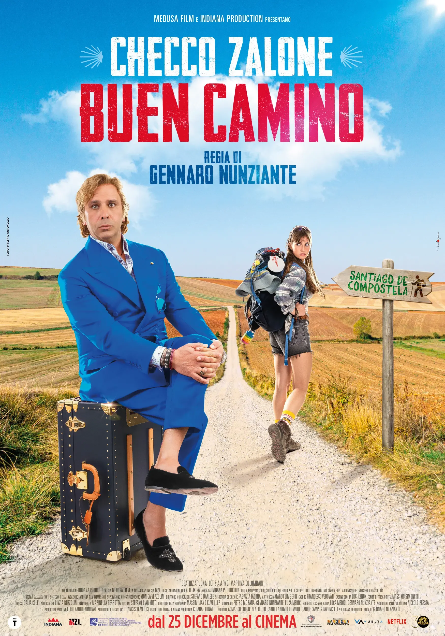 Locandina del film comico Buen Camino con Checco Zalone e sua figlia, su una strada di campagna con cielo azzurro e nuvole, e un cartello che indica Santiago de Compostela.