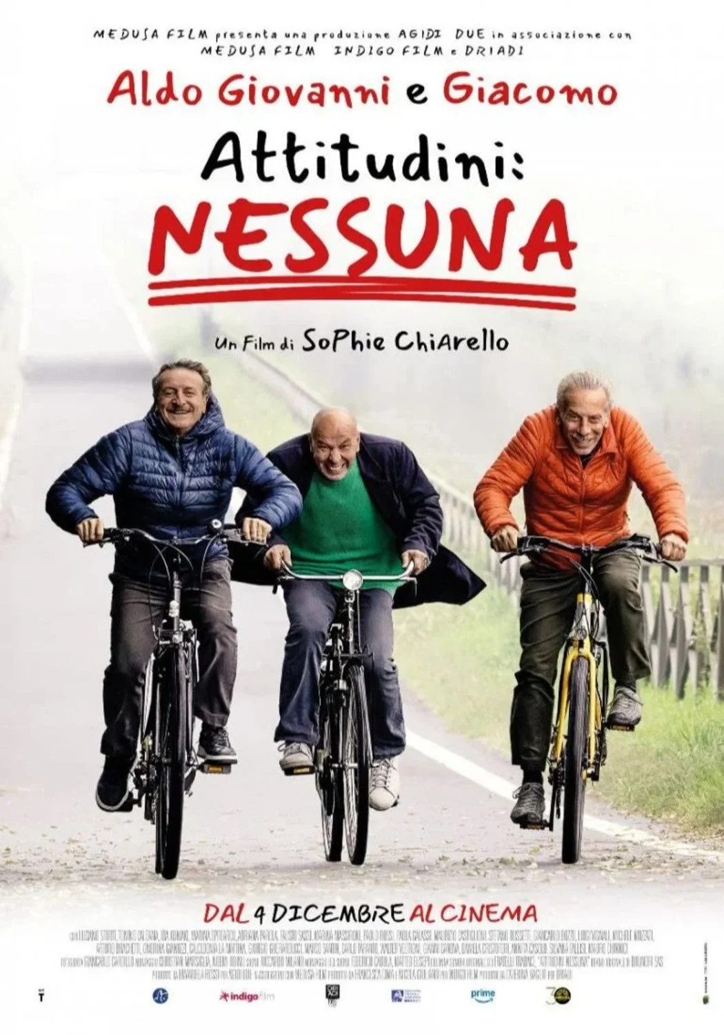 Locandina del film italiano 'Attitudini: Nessuna' con Aldo, Giovanni e Giacomo che vanno in bicicletta, sorridenti e vestiti casual.