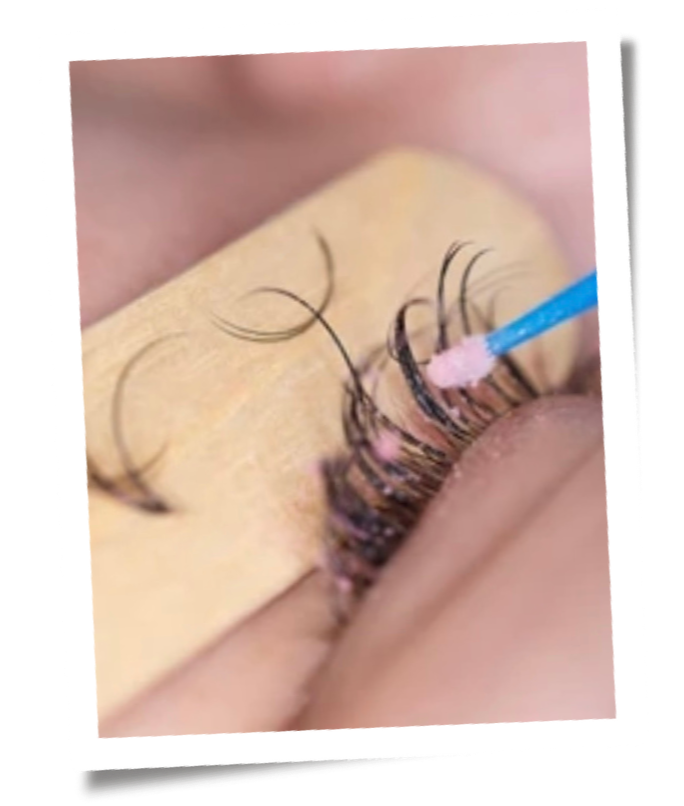 Applying eyelash extension with a tweezers on a person's eye.
