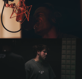 Two men in a recording studio; one is singing into a microphone, the other is standing nearby.
