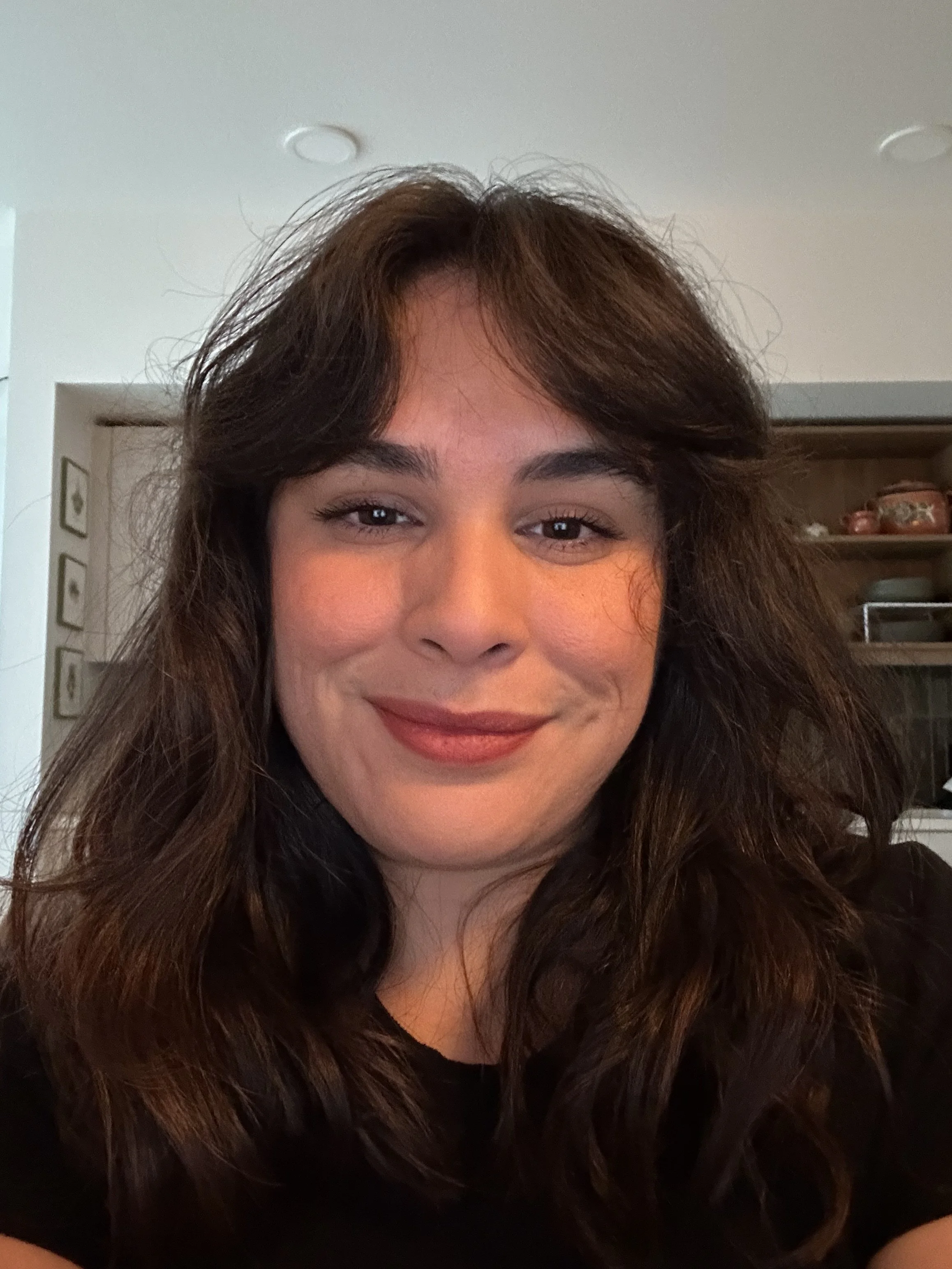 Portrait of a woman with long, wavy brown hair and a warm smile.