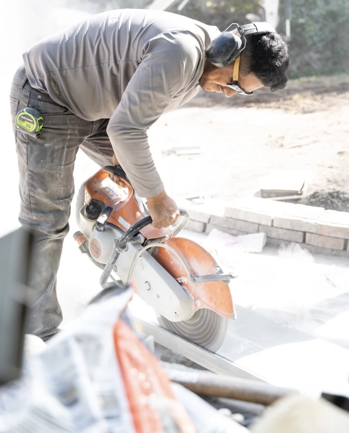 A man working with a large circular saw at a construction site, cutting bricks.
