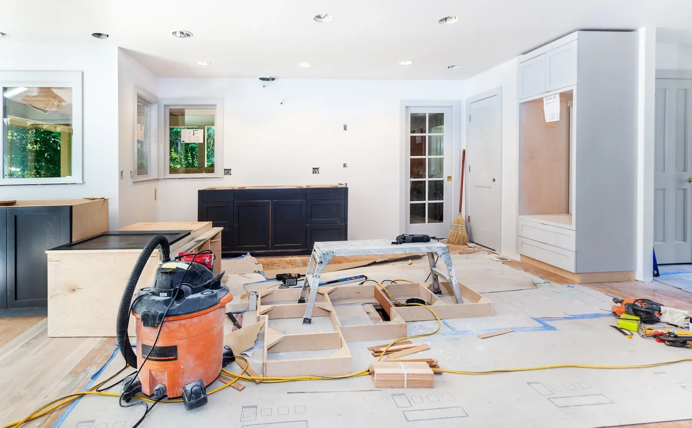 Kitchen under construction with tools, wooden cabinets, and electrical wiring.