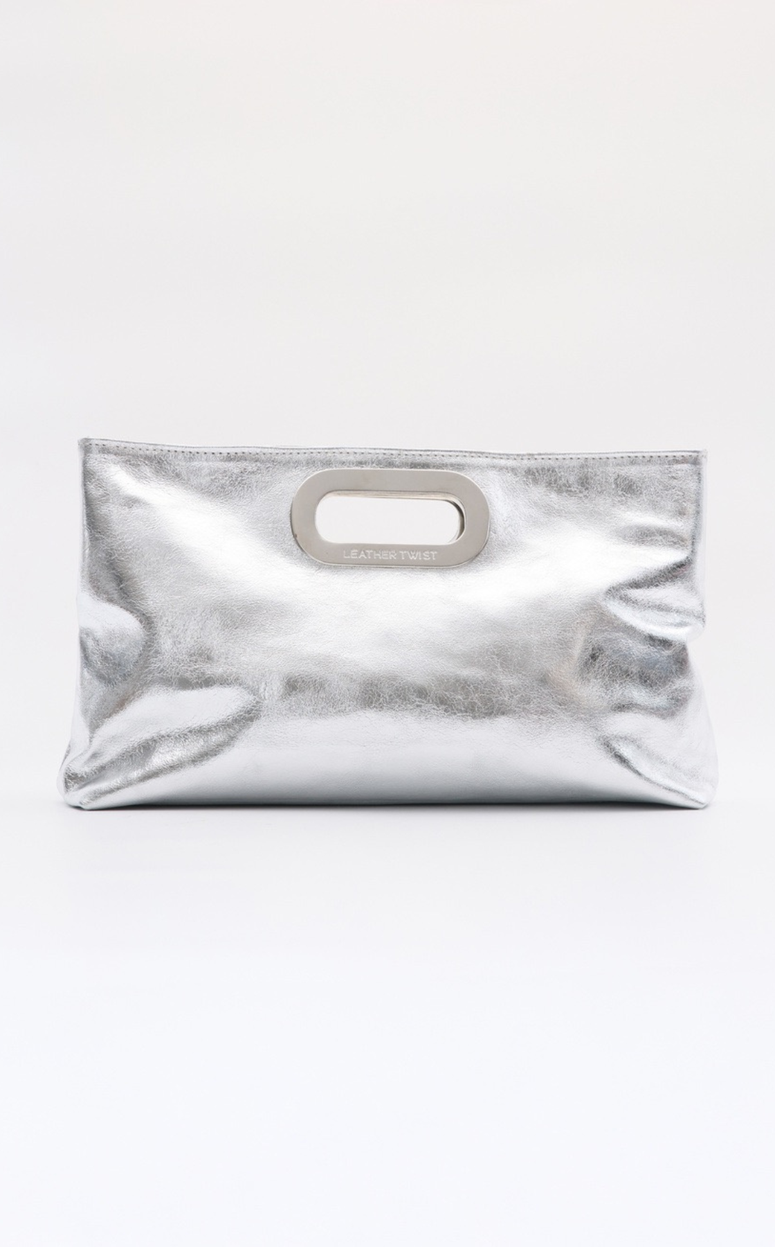 A silver metallic clutch purse with a cut-out handle and the words 'Leather Twist' on it, placed against a plain white background.