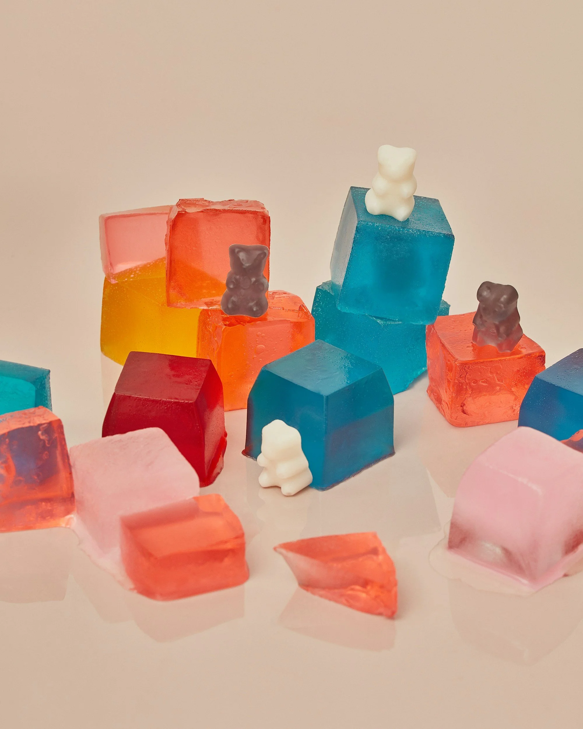 Colorful gummy bear and jelly candies in pink, orange, yellow, blue, and red, some shaped like bears, scattered on a white surface.
