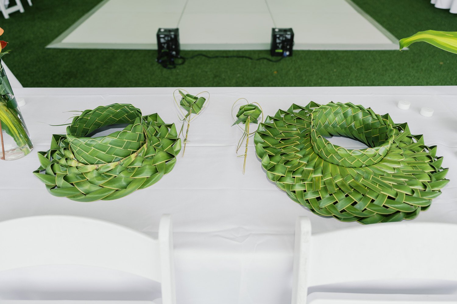 Two circular arrangements of woven green palm leaves on a white table, with small matching palm leaf decor in the center.
