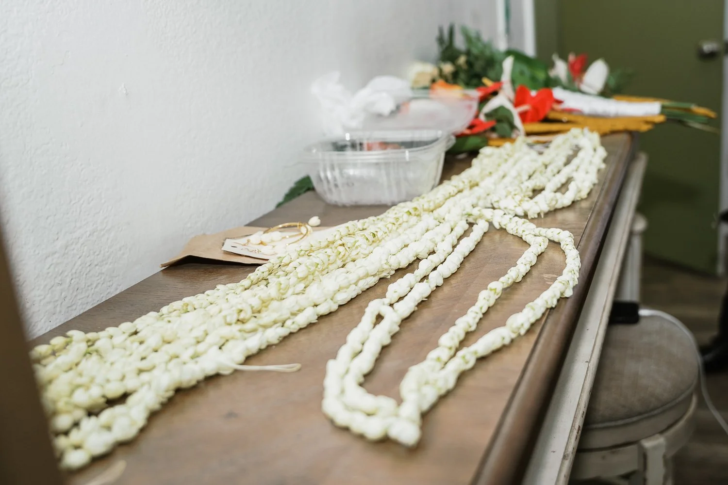 Flower garlands on a wooden table with flowers and craft supplies in the background.