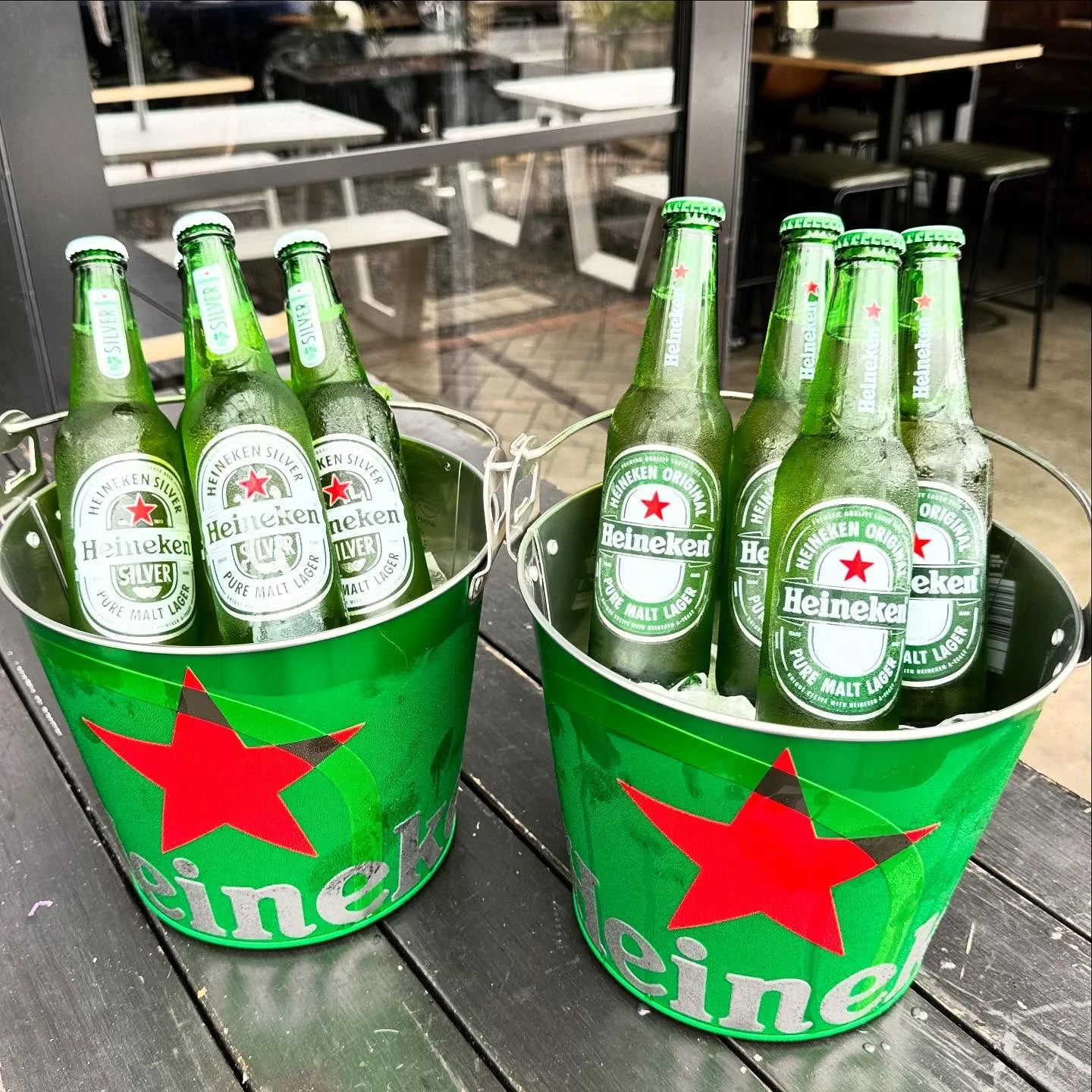 Two buckets of beer, one with cold Heineken & one with Heineken Silver Beer bottles on a wooden table outside Little Ed Pukekohe.