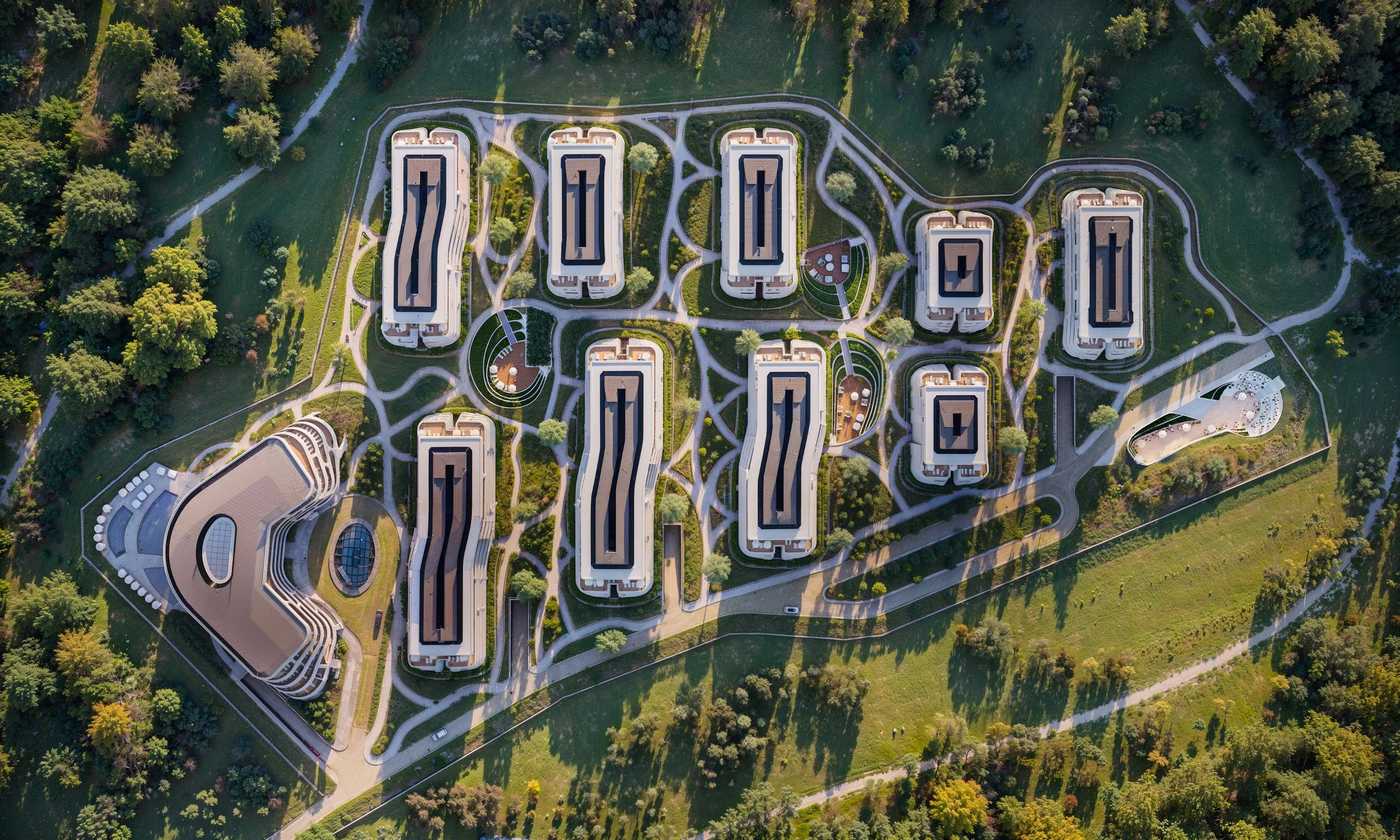 Aerial view of a modern residential complex with multiple high-rise buildings surrounded by green trees and walking paths. Kamil Rombczyk portfolio architectural vizualization.  Kamil Rombczyk portfolio architectural vizualization. Kamil Rombczyk por