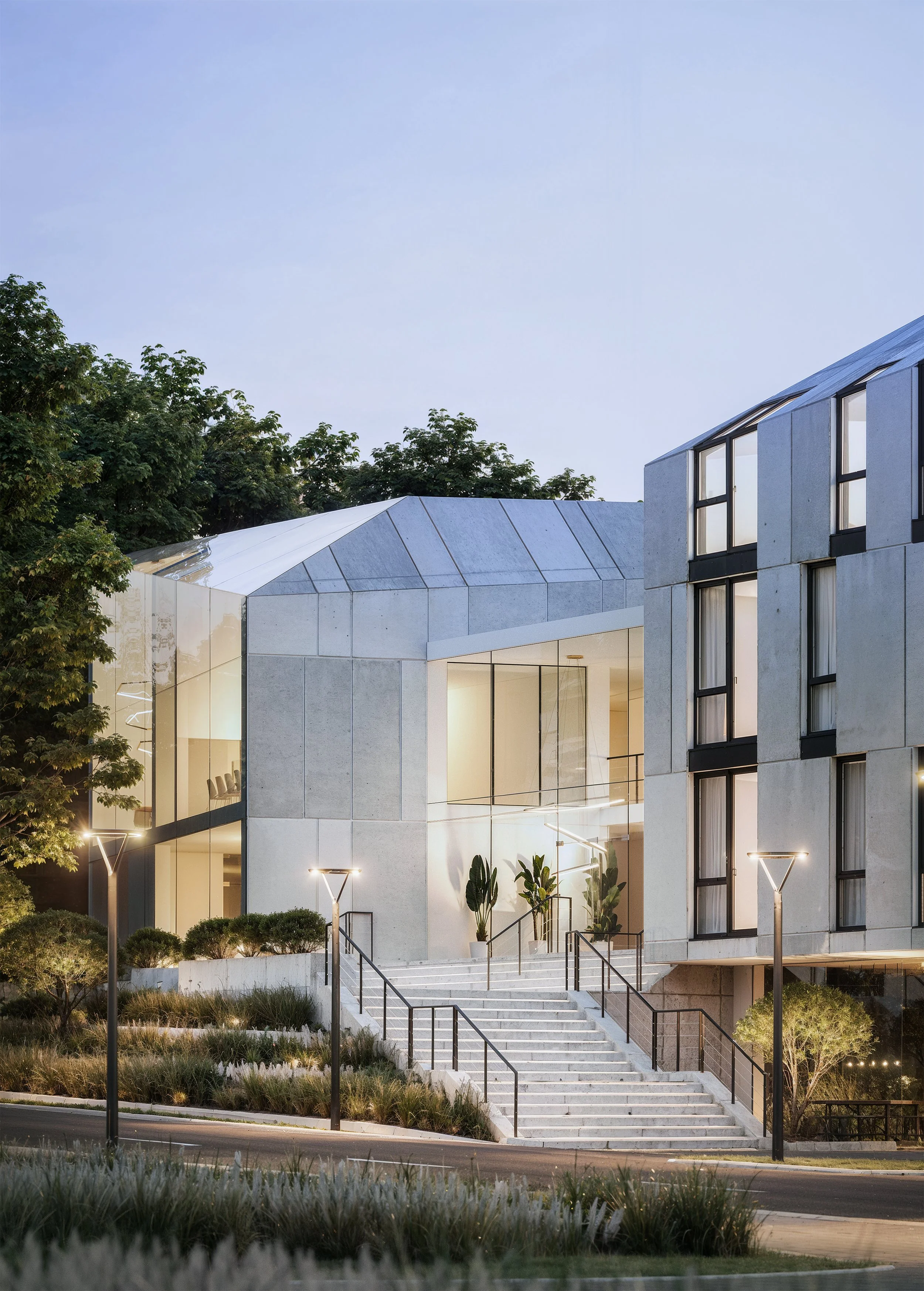 A sleek, modern architectural building with large glass windows and geometric forms, surrounded by landscaped greenery and elegant staircases. Kamil Rombczyk portfolio architectural vizualization. Kamil Rombczyk portfolio wizualizacje architektoniczn