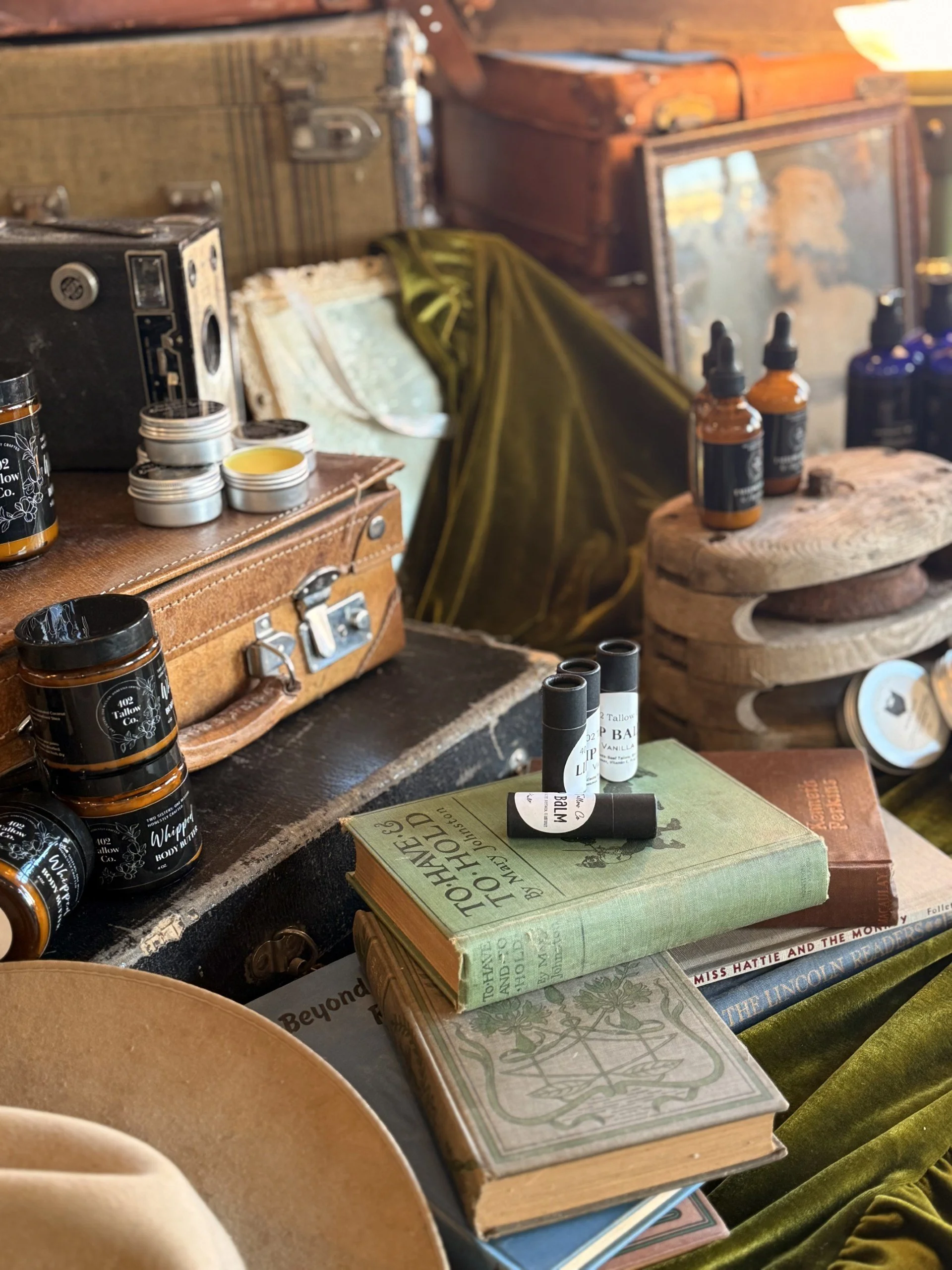 A vintage desk with old books, small jars, and bottles, surrounded by antique items and a cozy, rustic setting.