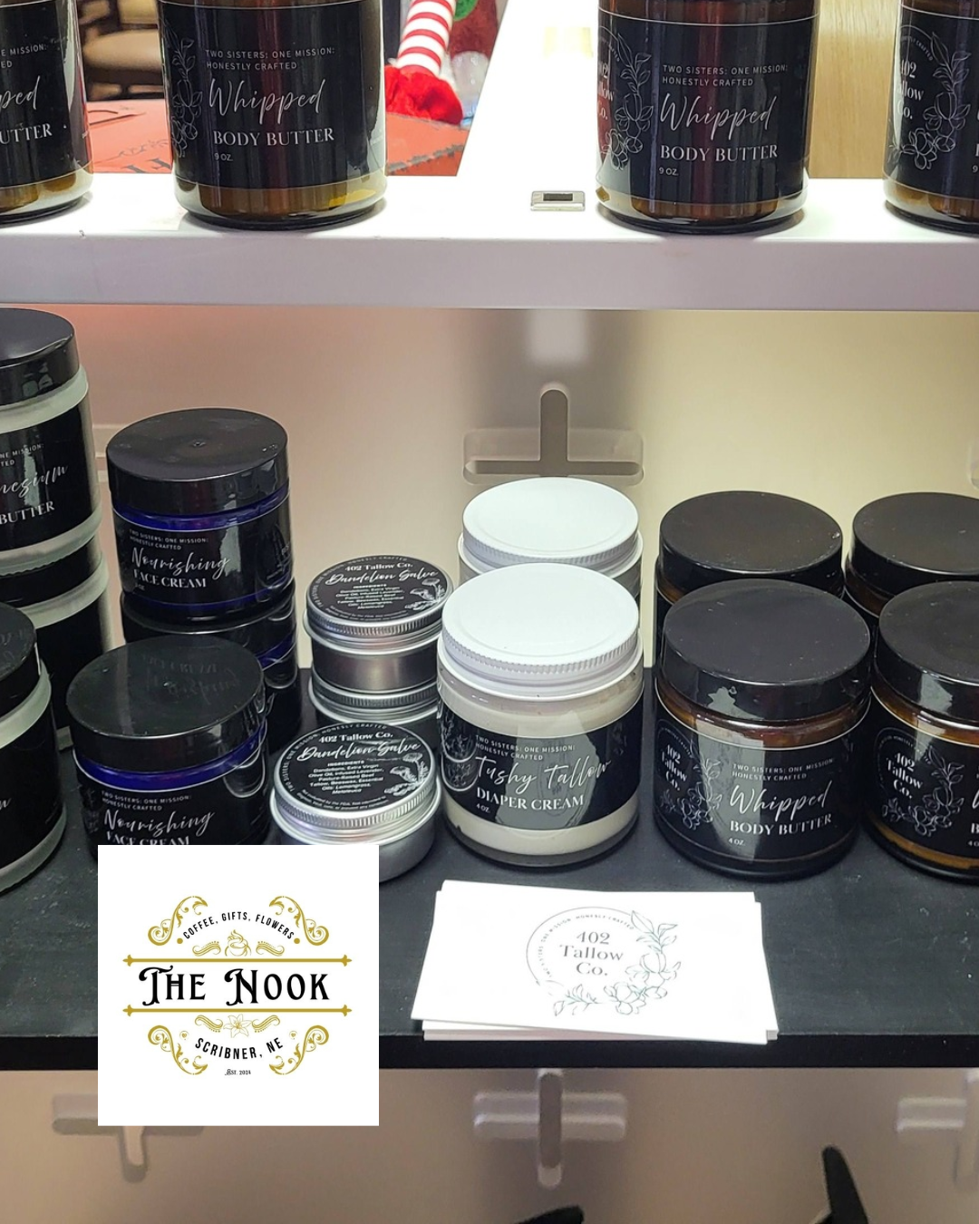 Display of body care products, including whipped body butter, nourishing face cream, and other skincare items on a store shelf, with business cards for 'The Nook' in Scriober, NE.