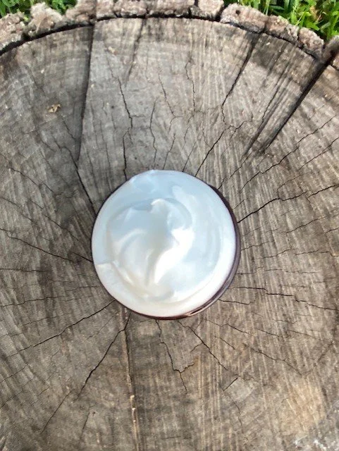 Display of skincare tallow products on a wooden table with handwritten labels indicating 'Locally Made'.