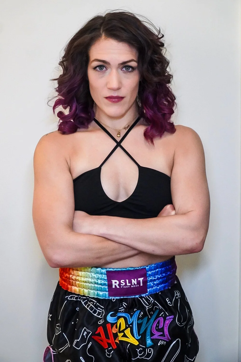 High Kick's instructor, Rae Switlick, Certified Krav Maga coach and self-defense trainer, wearing a black top and rainbow and black boxing shorts.