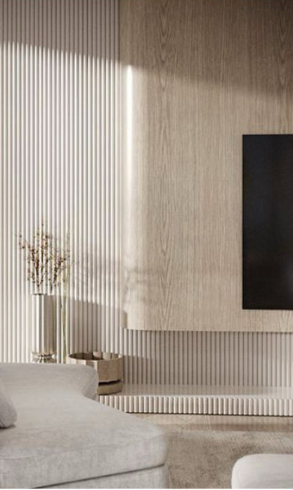 Living room with vertical striped wall, wooden panel, and a flat screen TV on the wall. A light-colored sofa and a vase with dried flowers are visible.